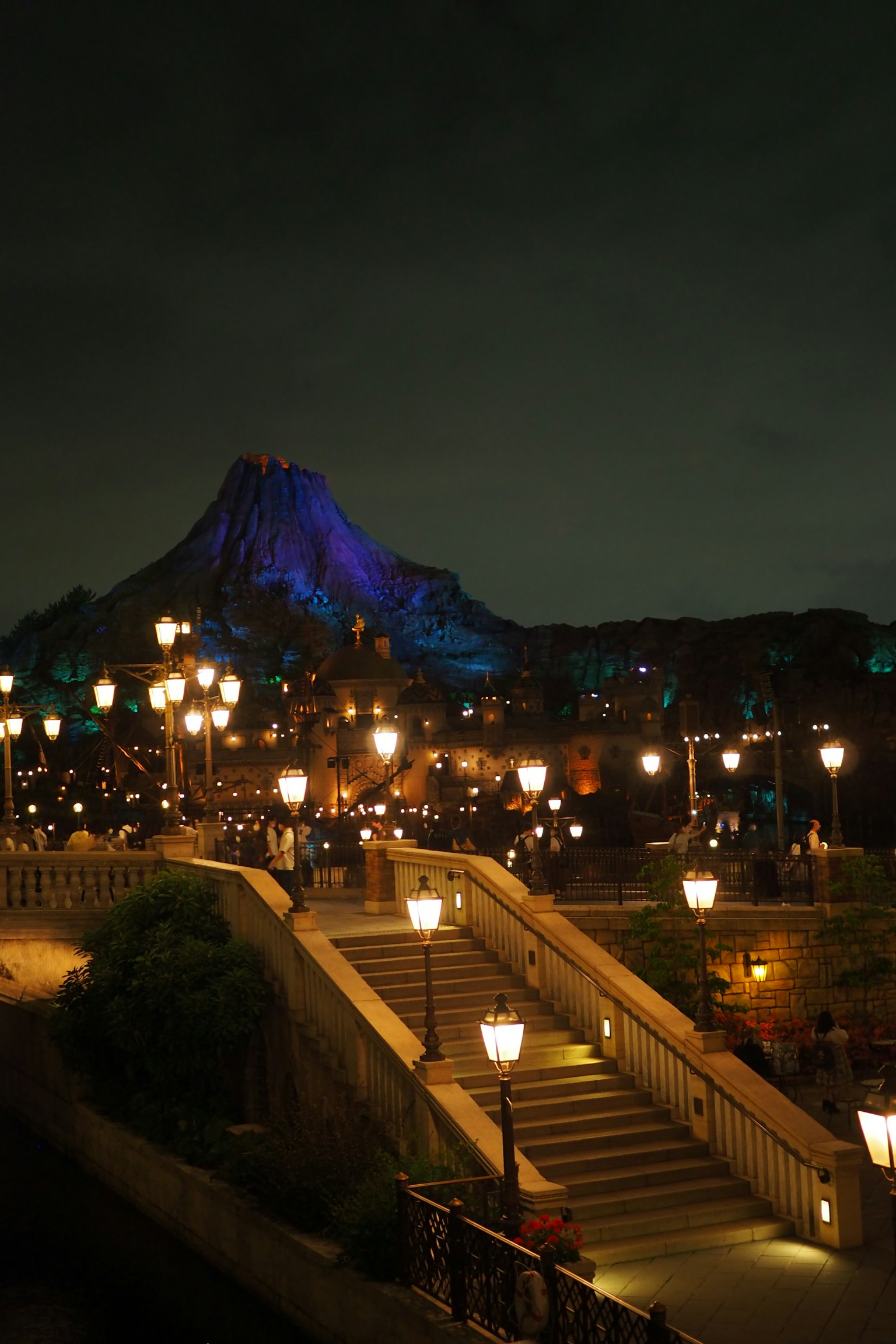 Una hermosa escena nocturna con escaleras iluminadas y farolas con una montaña brillante de fondo