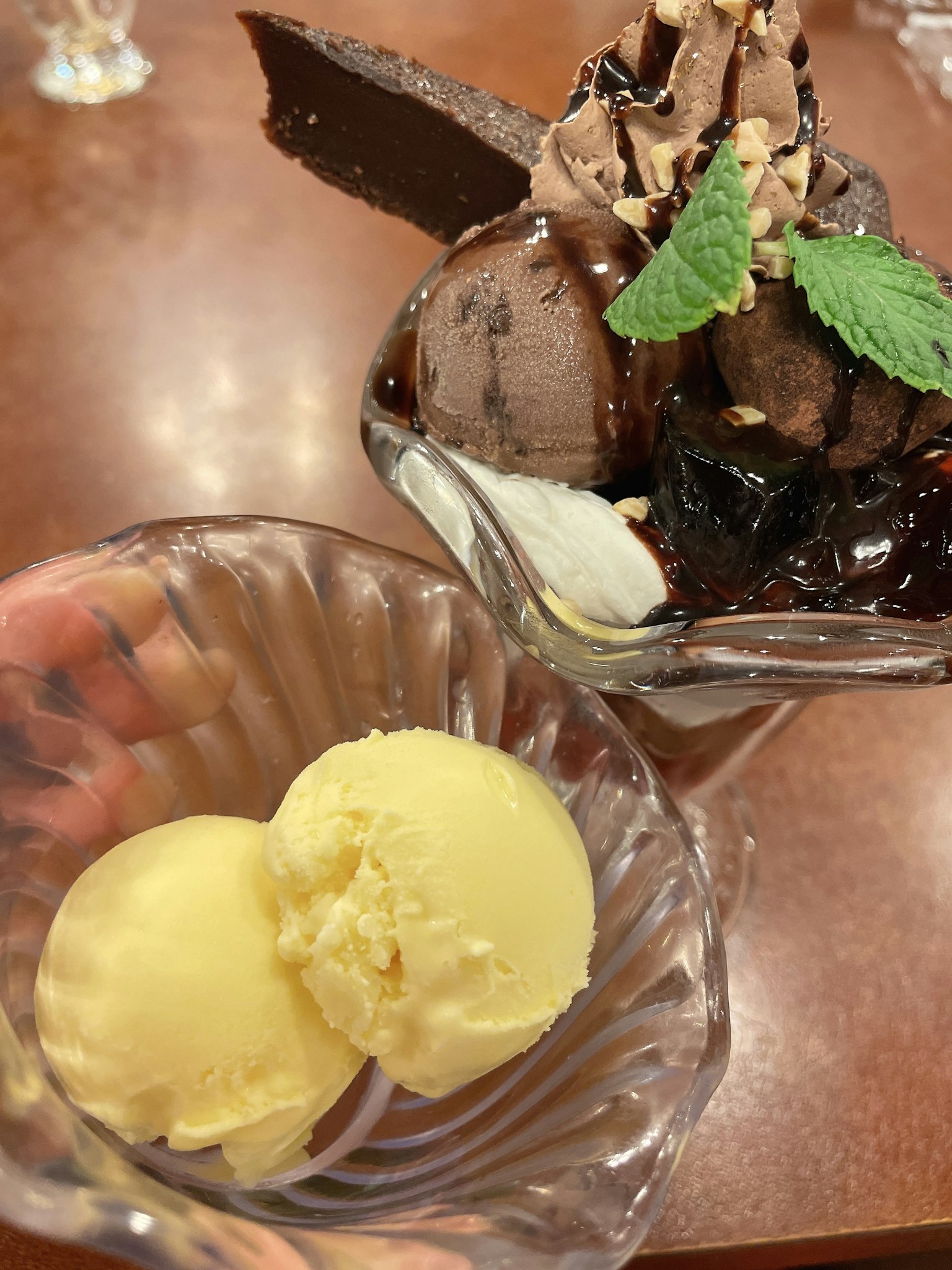 Un plat avec de la glace jaune et un parfait au chocolat avec des feuilles de menthe