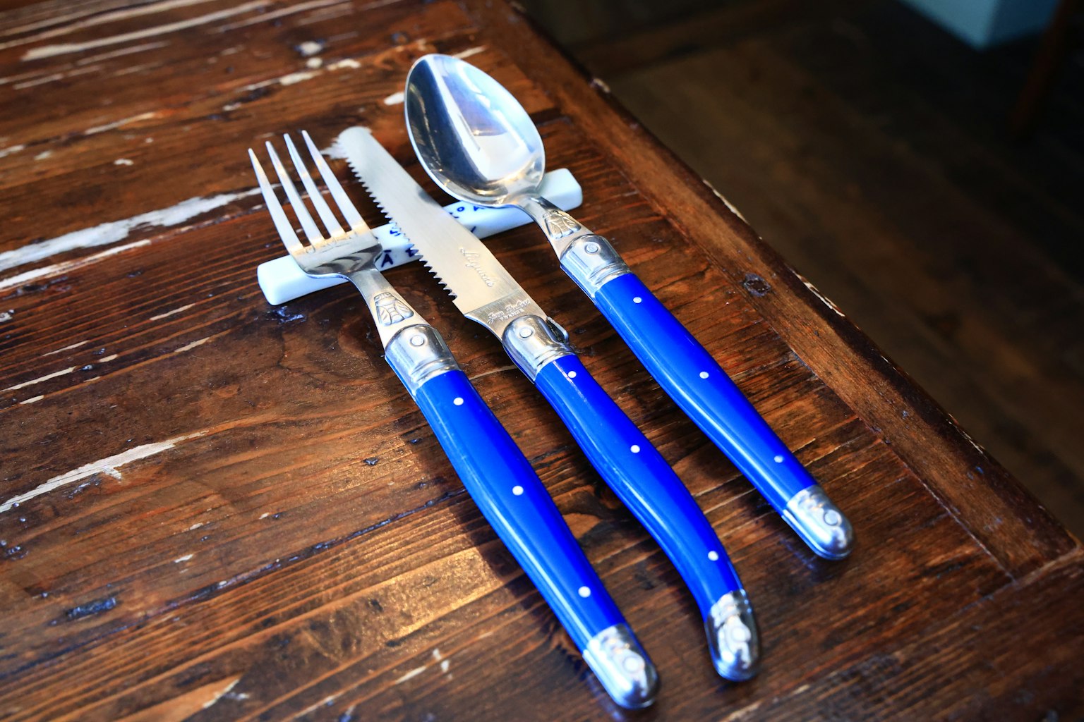 Un ensemble de couverts avec des poignées bleues disposées sur une table en bois