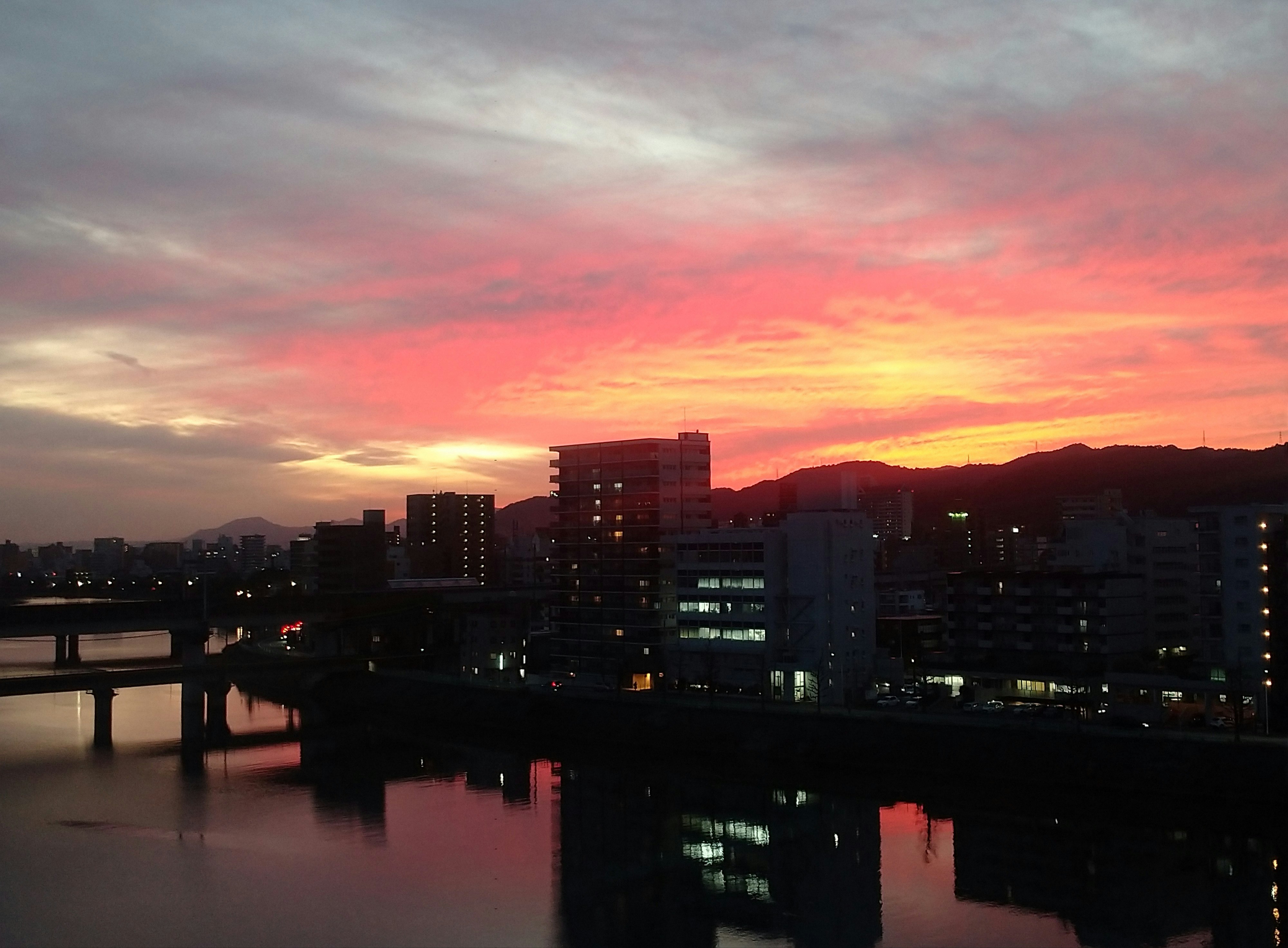 夕焼けの川沿いに広がる夜景の街並み