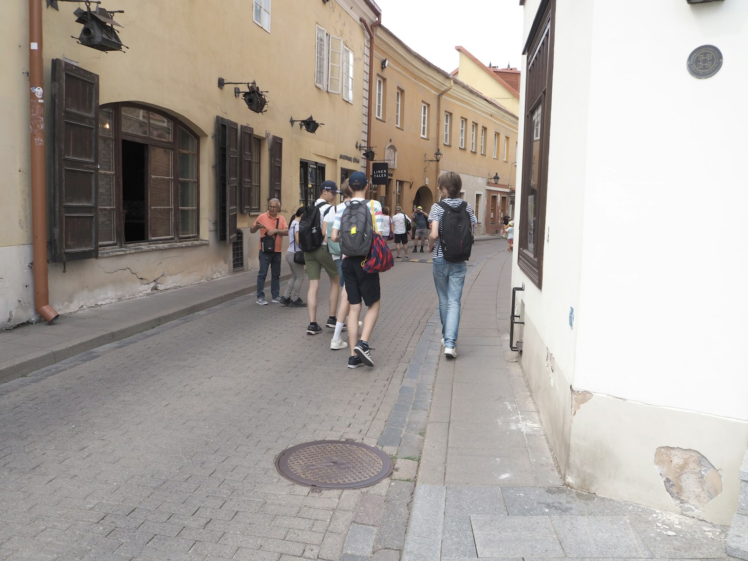 People walking down an old street with yellow buildings and open windows
