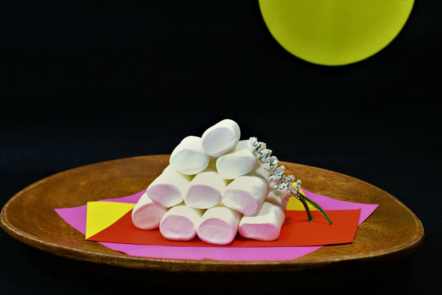A pyramid of marshmallows on colorful paper with a yellow circle in the background