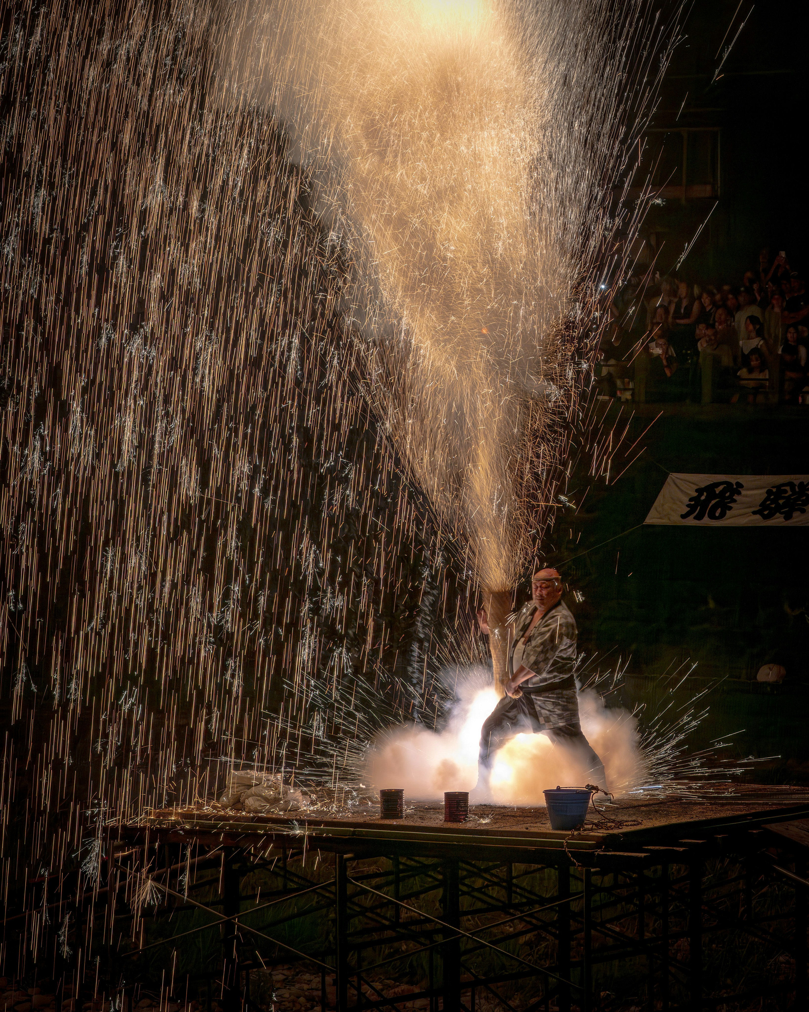 火花が飛び散る中でパフォーマンスをする男性の姿