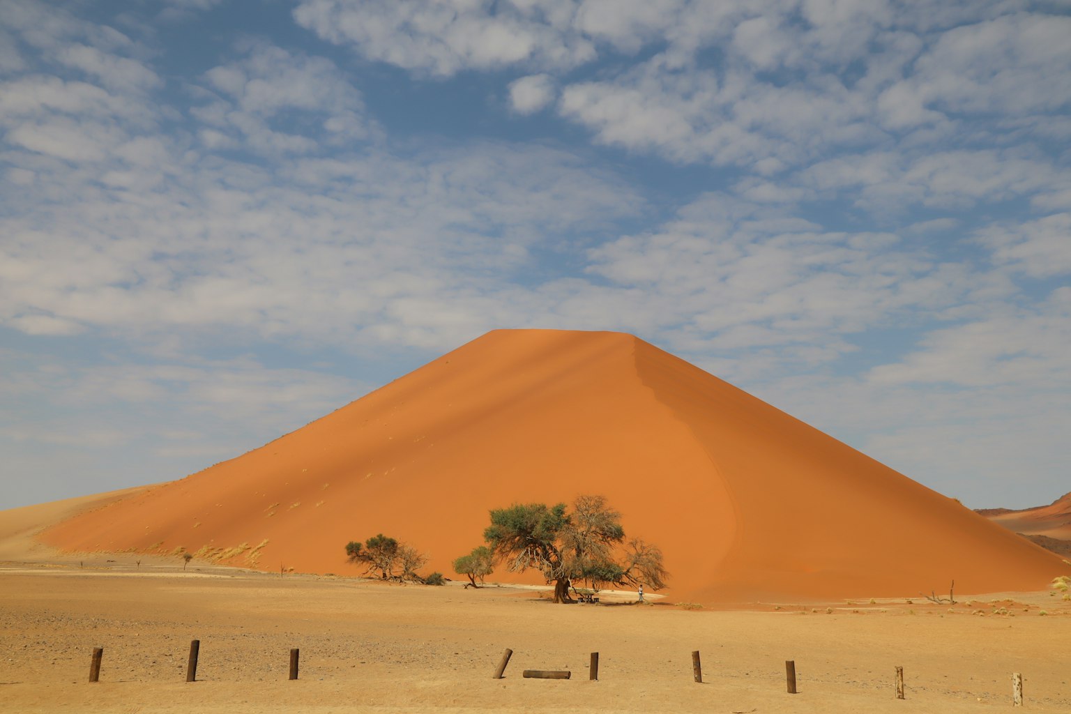 Red sand dune in Namibia with blue sky and scattered clouds