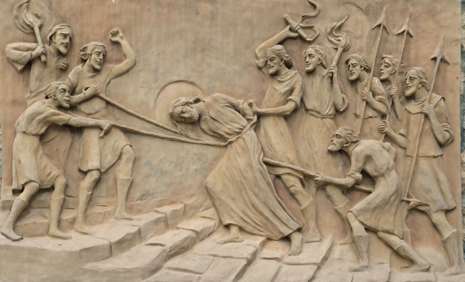 Une scène sculpturale représentant une figure retenue de force par plusieurs autres