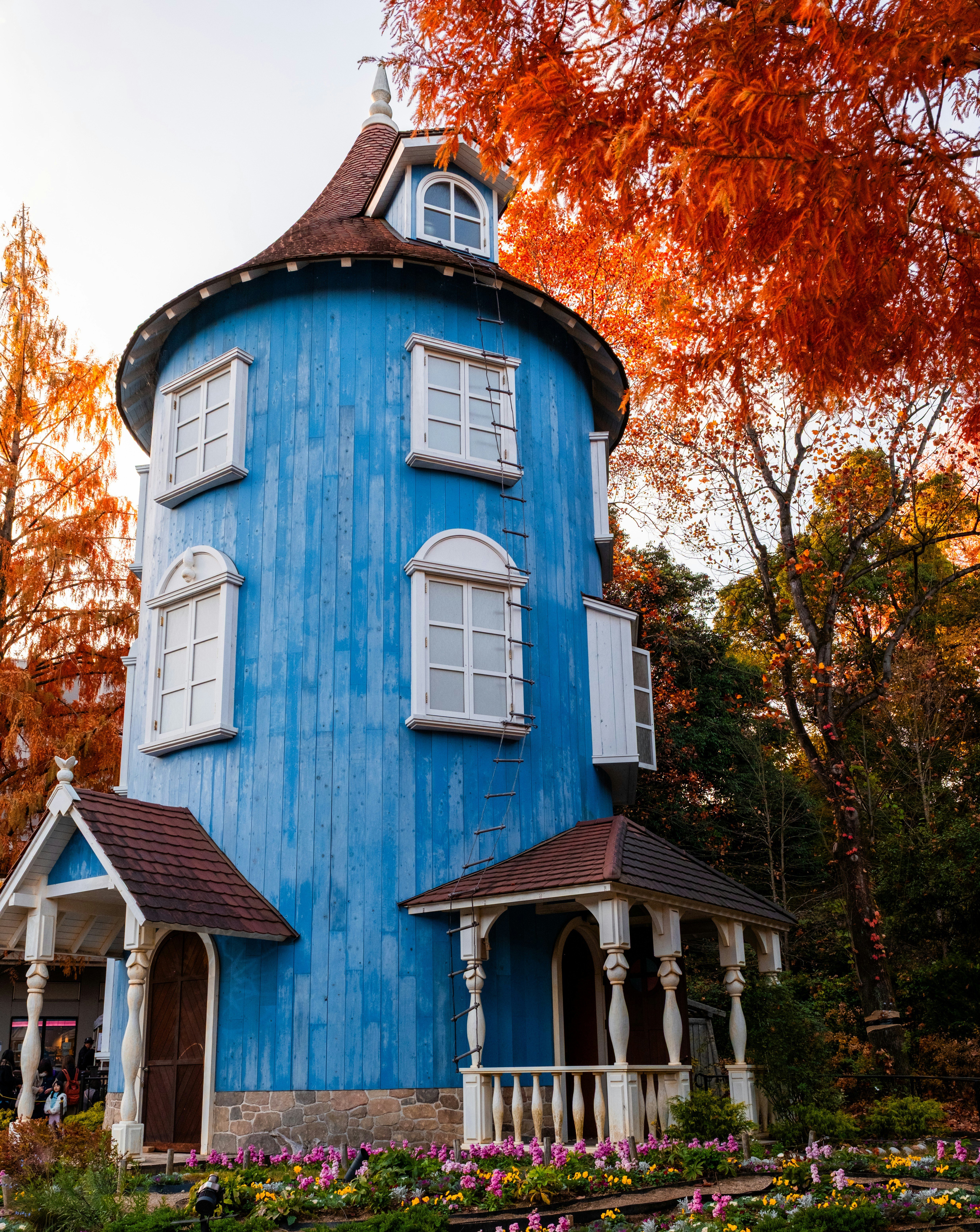 Blue round house surrounded by vibrant autumn foliage