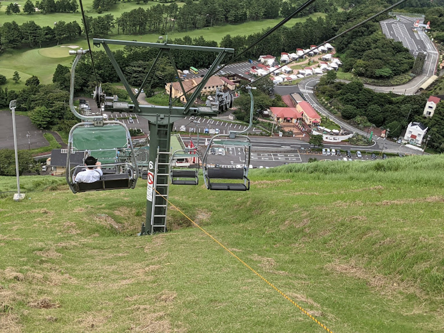 Vue d'un télésiège sur une colline verte et une ville en contrebas
