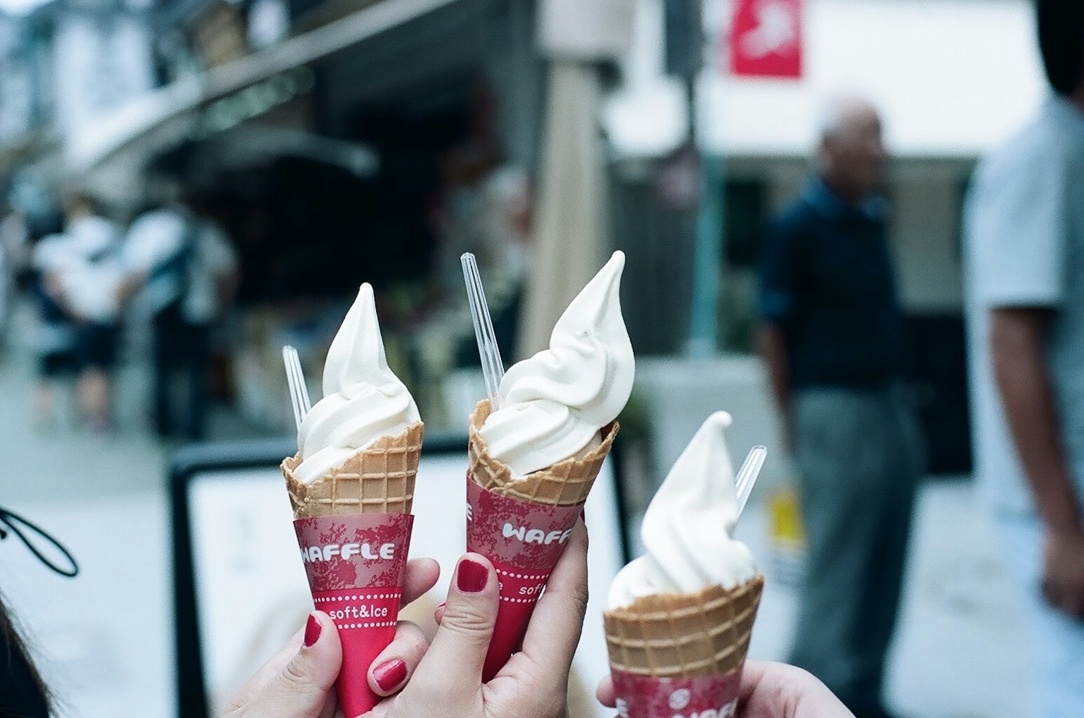 Tiga cone es krim dipegang di tangan dengan es krim lembut