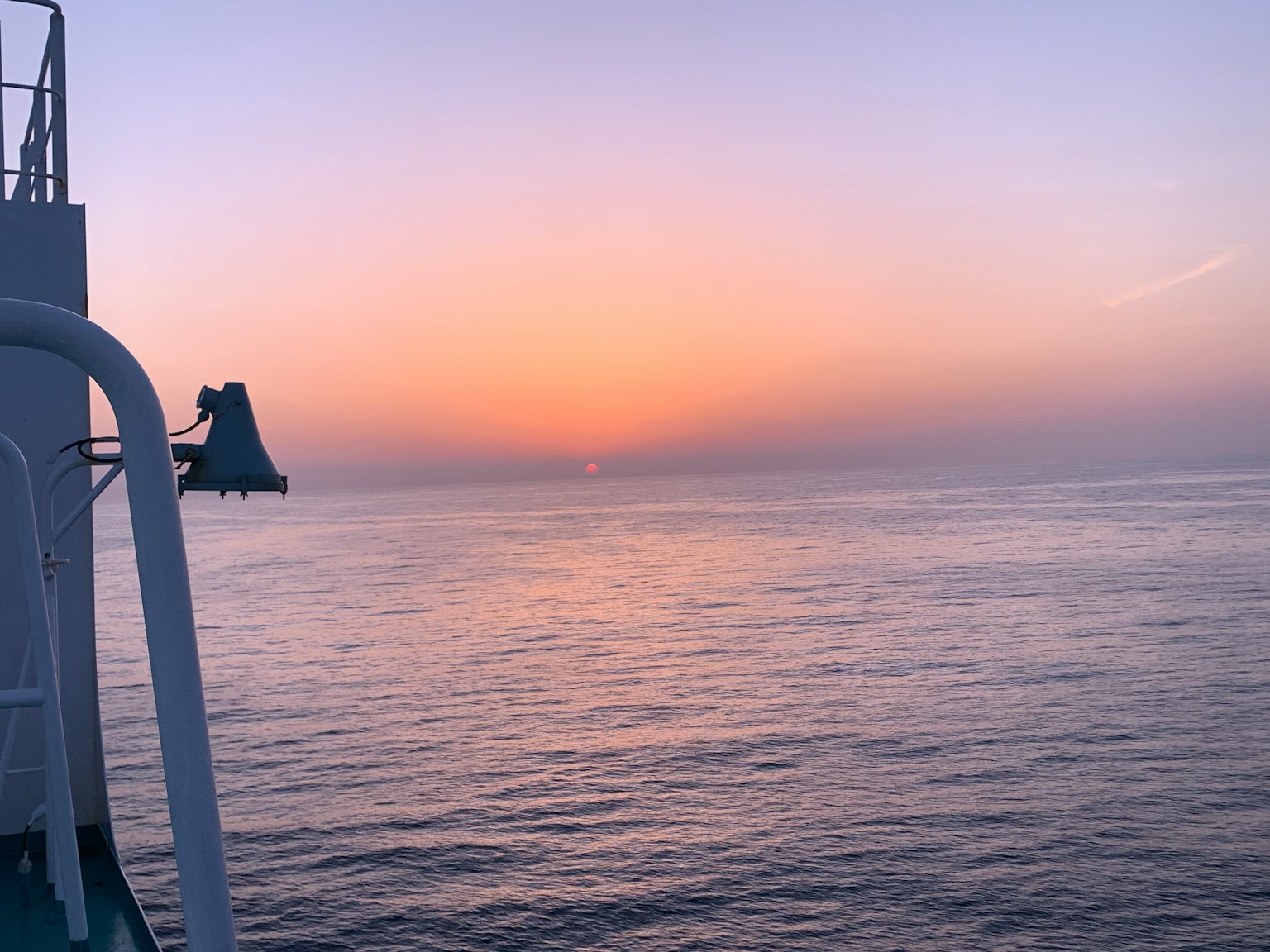 Mer calme avec ciel au coucher du soleil montrant une partie d'un navire à gauche