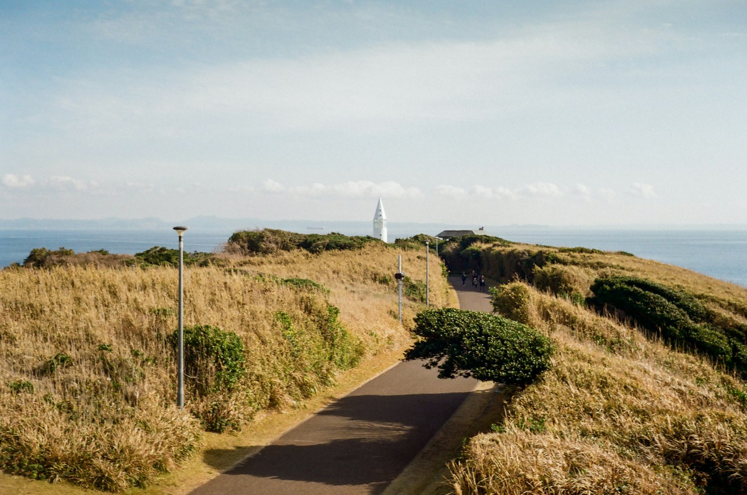 Vista panoramica di un sentiero che conduce a un faro su una collina erbosa vicino al mare
