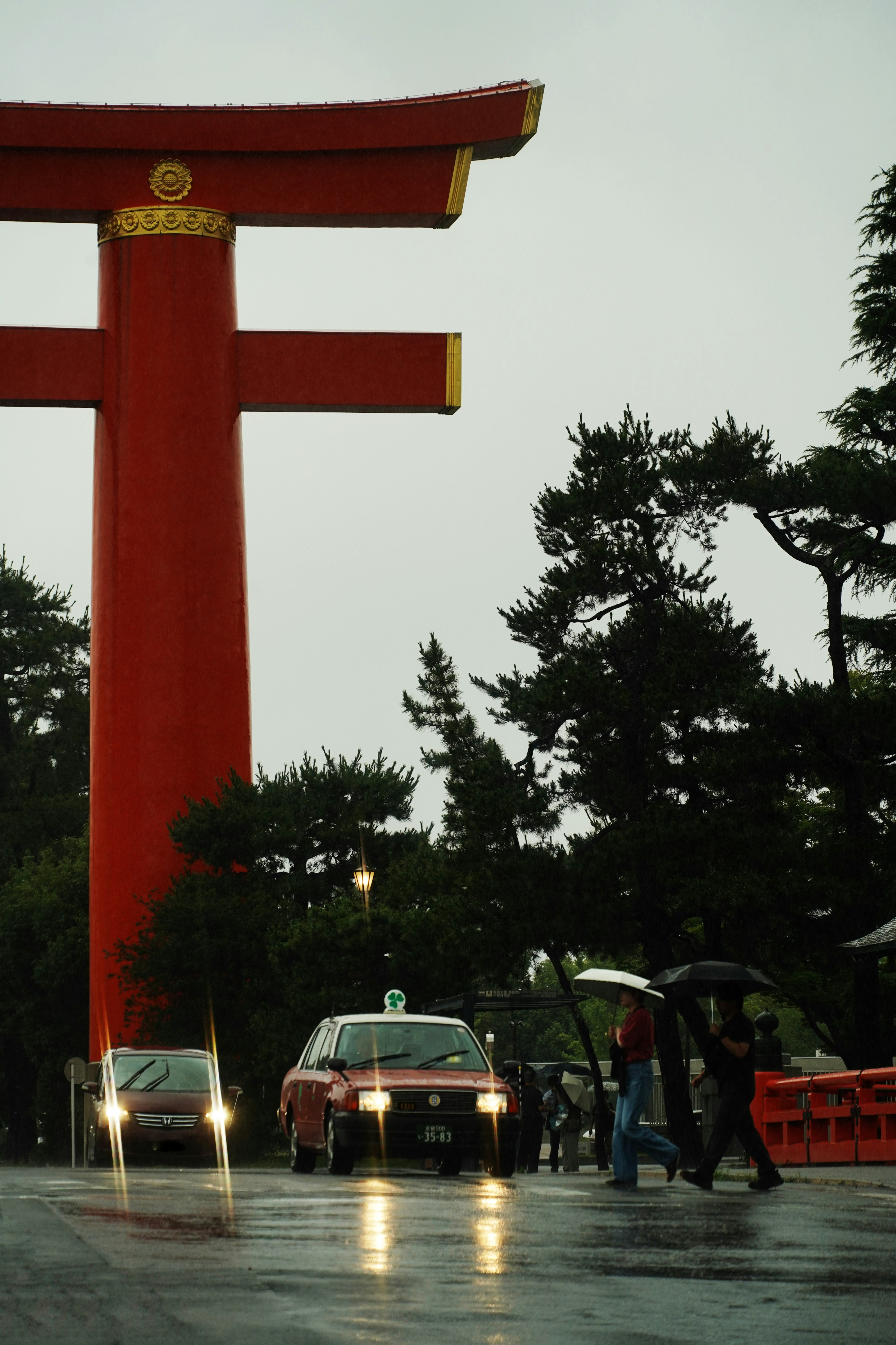 雨の平安神宮の朱塗り大鳥居と参道の人々