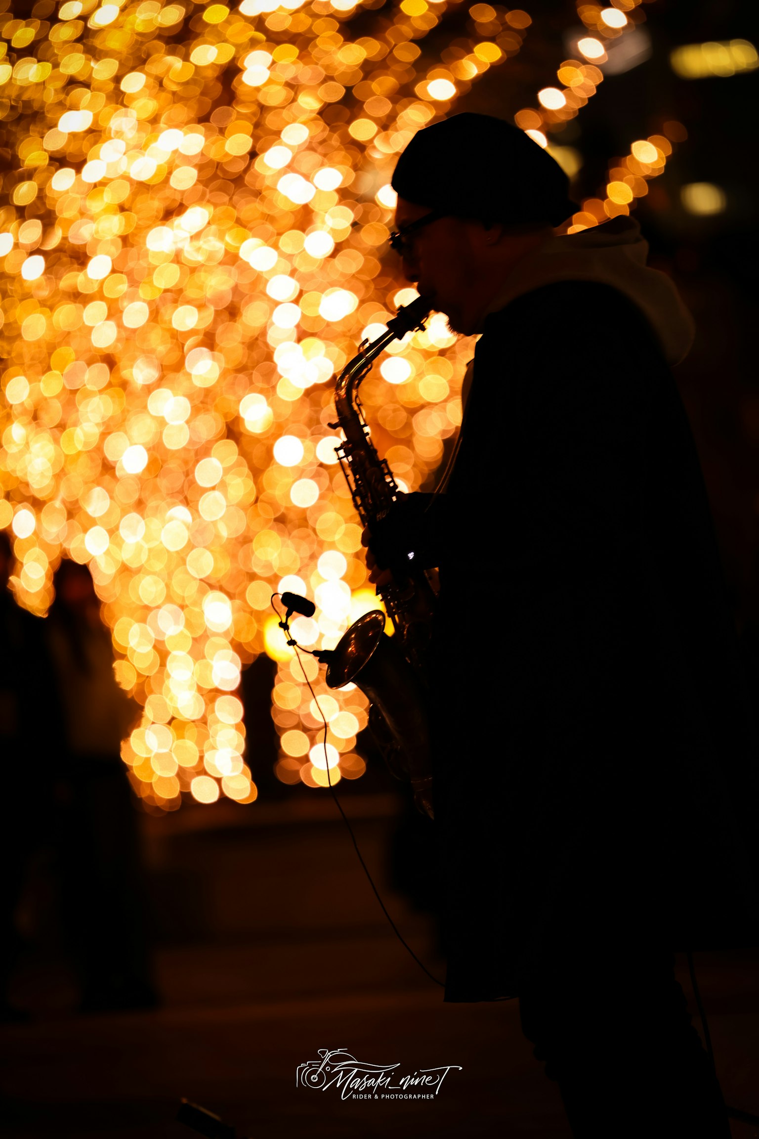 サックスを演奏するシルエットの男性と背景のぼんやりした光