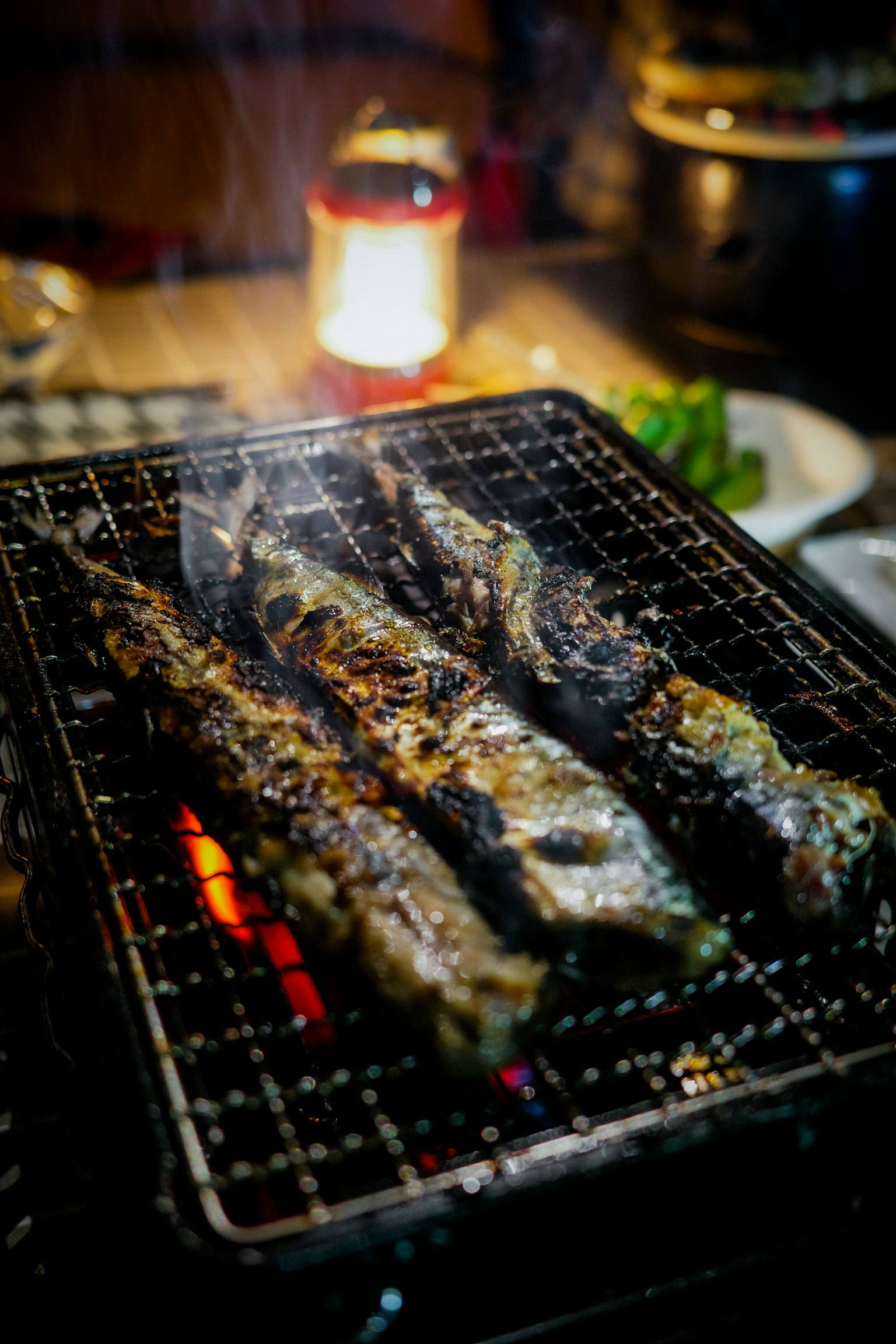 Brochettes de poisson grillées avec de la fumée s'élevant d'un grill au charbon