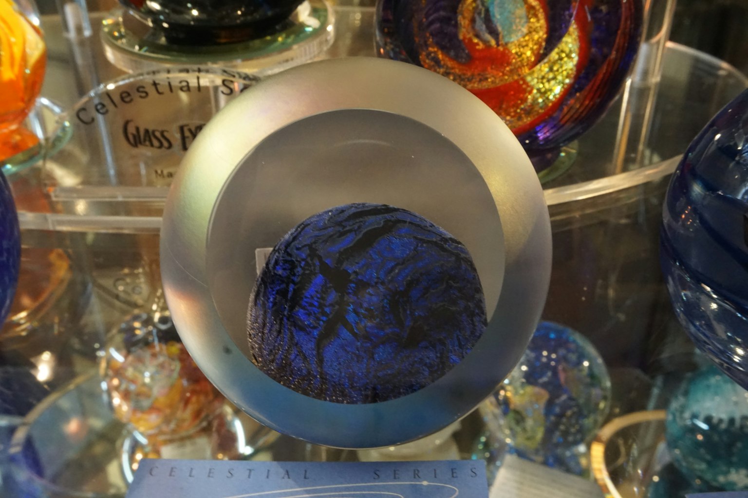 Eine blaue Glas-Sphäre auf einer transparenten runden Basis platziert