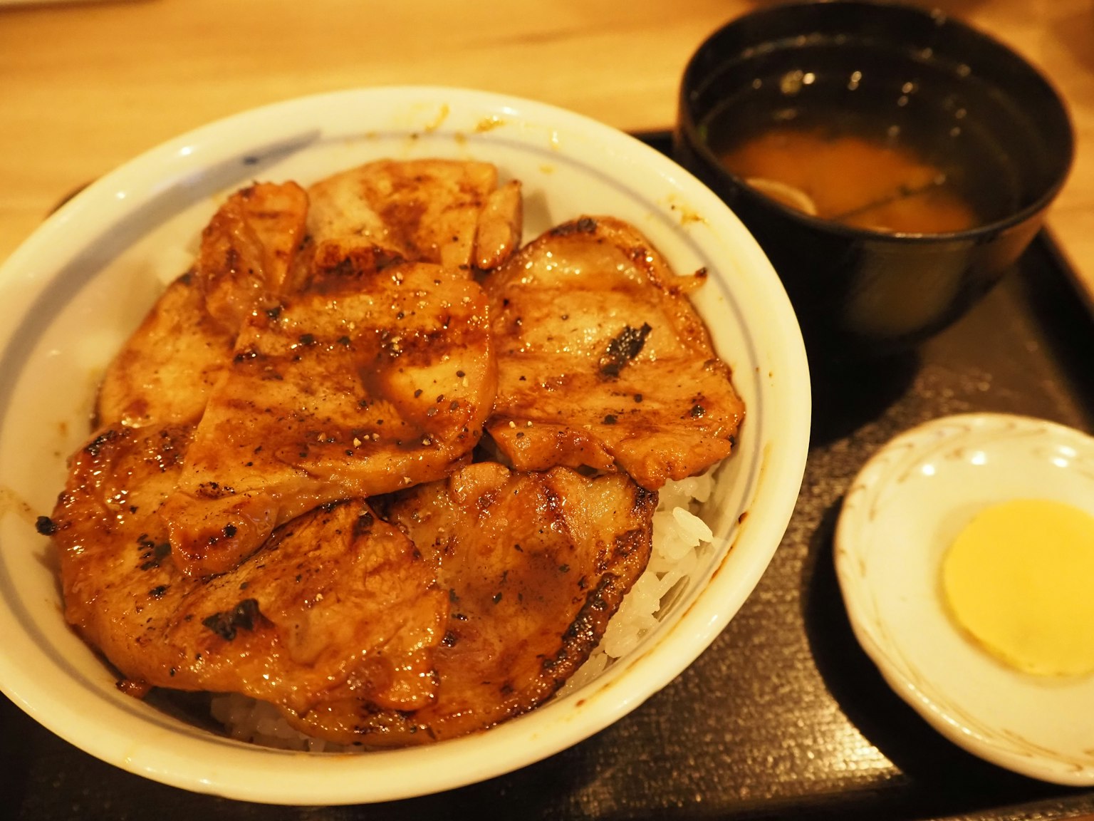 一碗米饭上放着烤猪肉和一碗味噌汤