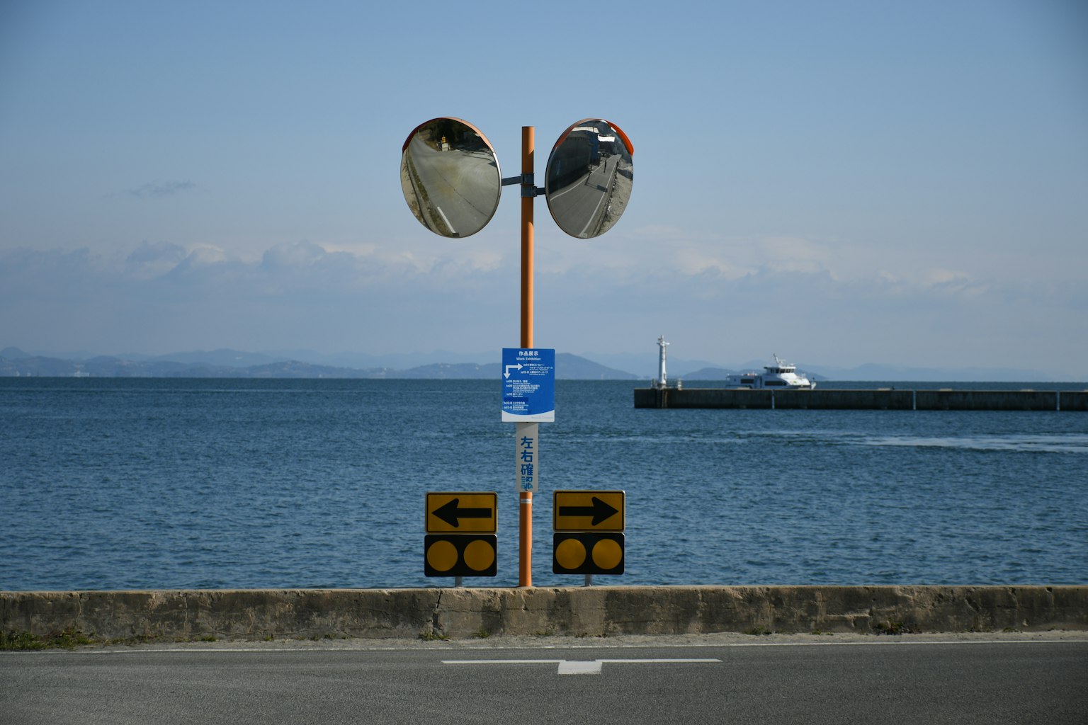 Segnali stradali e specchi che sovrastano il mare e il porto