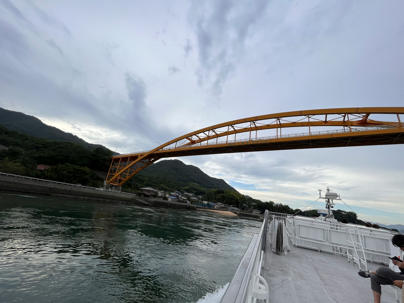 A yellow arch bridge spanning over water with mountains in the background