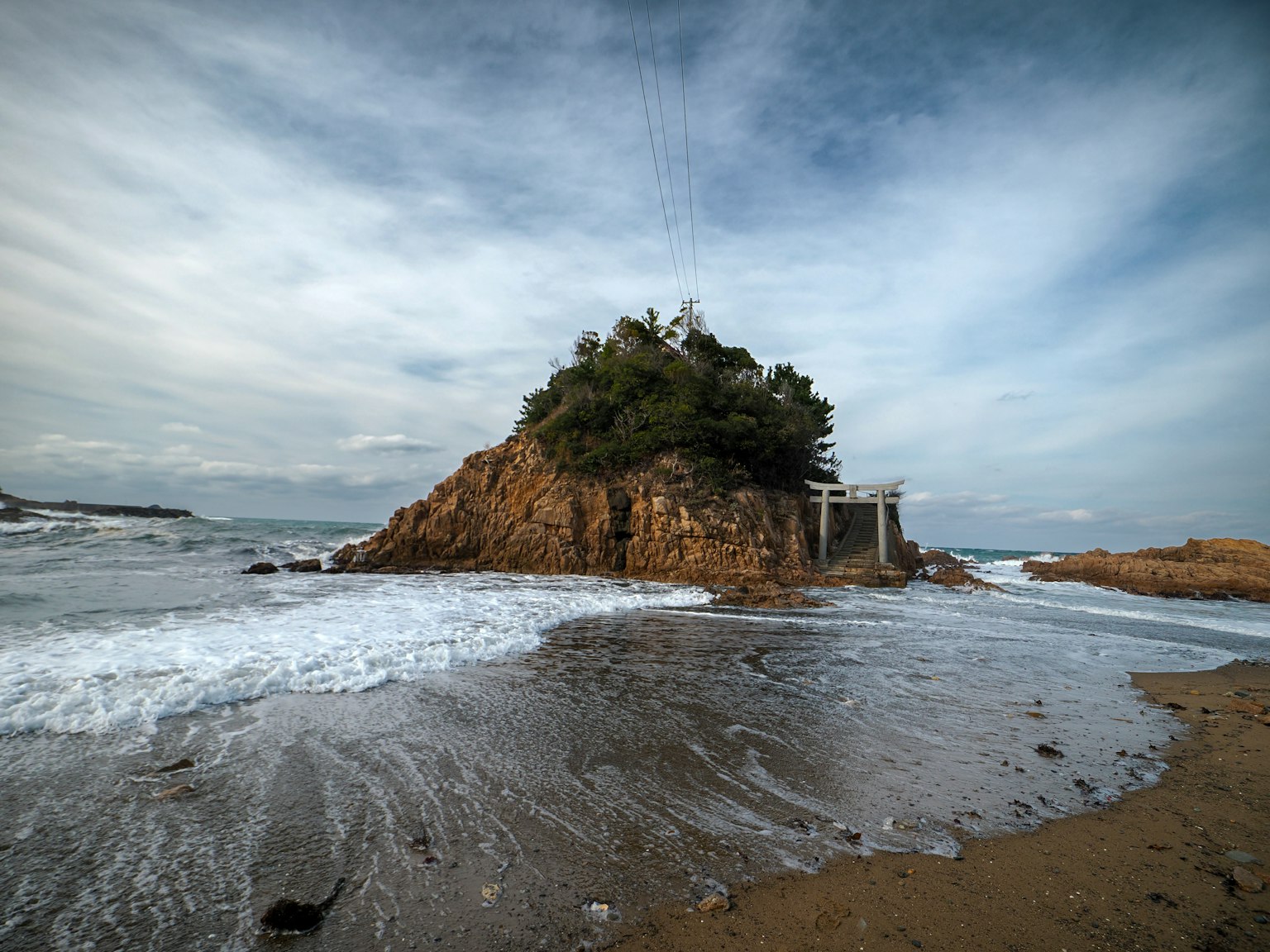 เกาะเล็ก ๆ ที่ชายฝั่งพร้อมคลื่นซัดชายหาดทราย