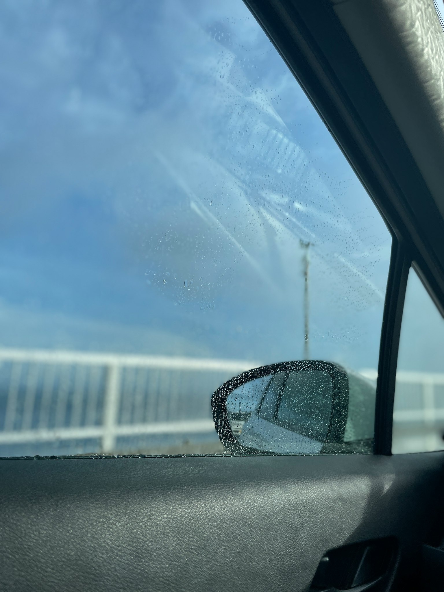 Pemandangan dari jendela mobil dengan tetesan air dan jembatan
