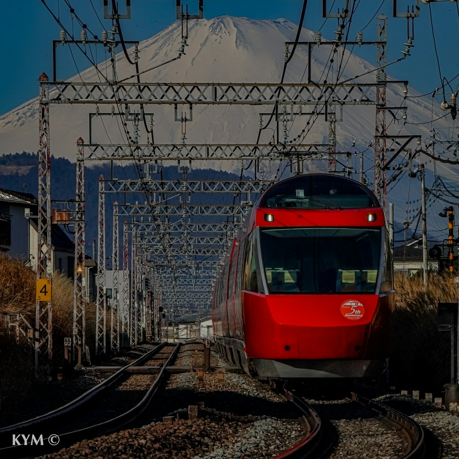 Treno rosso che corre sui binari con il Monte Fuji sullo sfondo