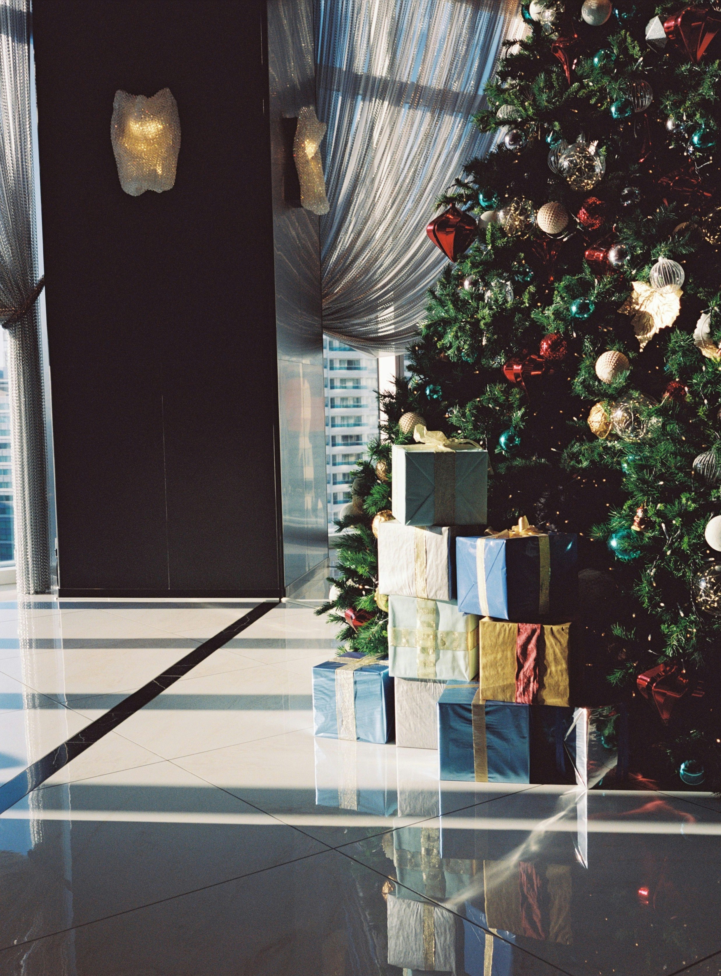 Pintu masuk indoor dengan pohon Natal dan kotak hadiah bertumpuk