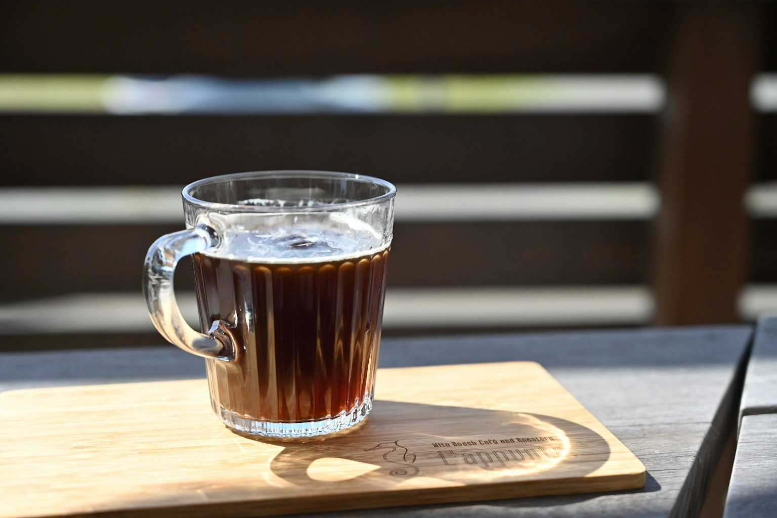 แก้วใสใส่กาแฟวางอยู่บนถาดไม้