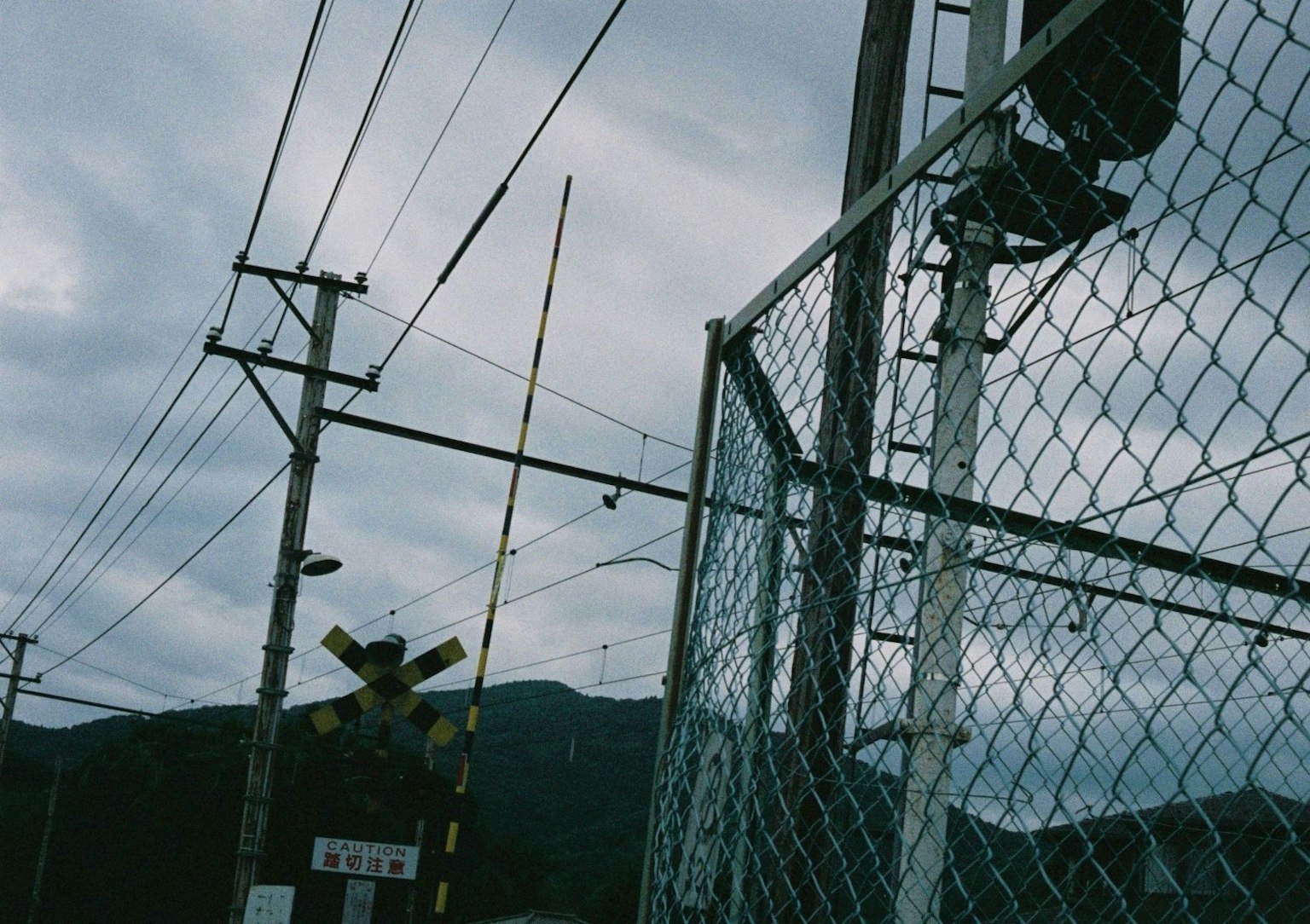 Paysage avec un passage à niveau et des lignes électriques sous un ciel nuageux