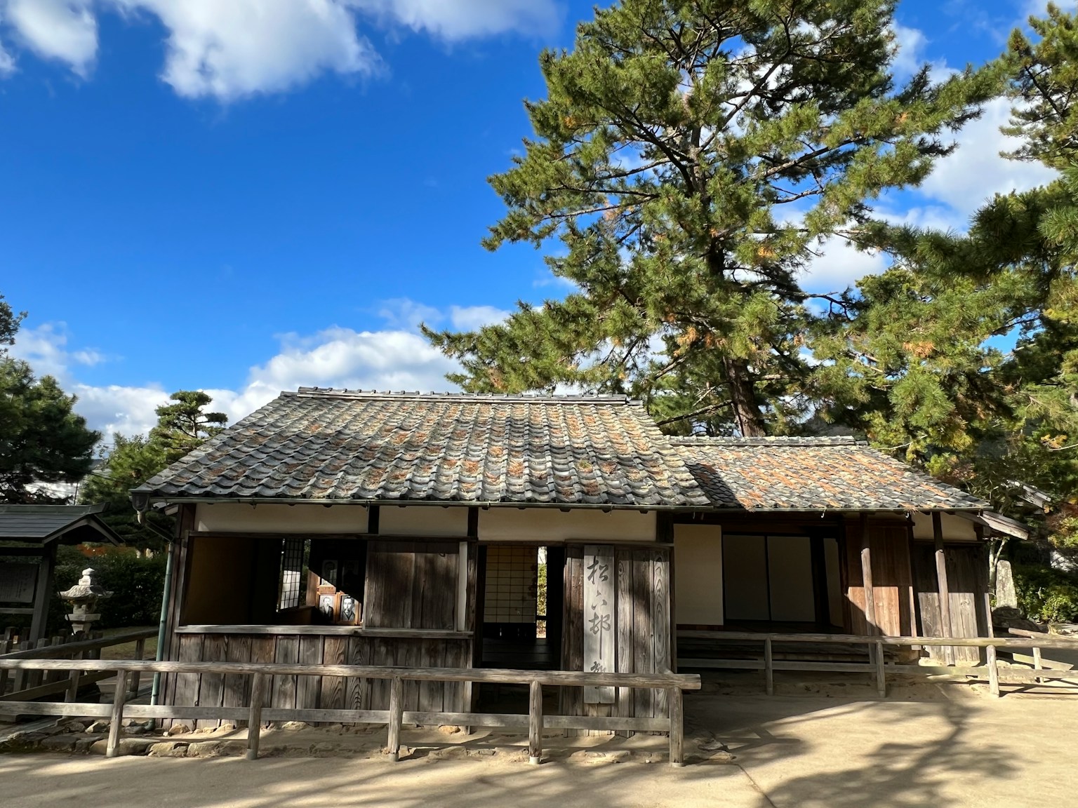 Exterior view of an old Japanese house under a pine tree