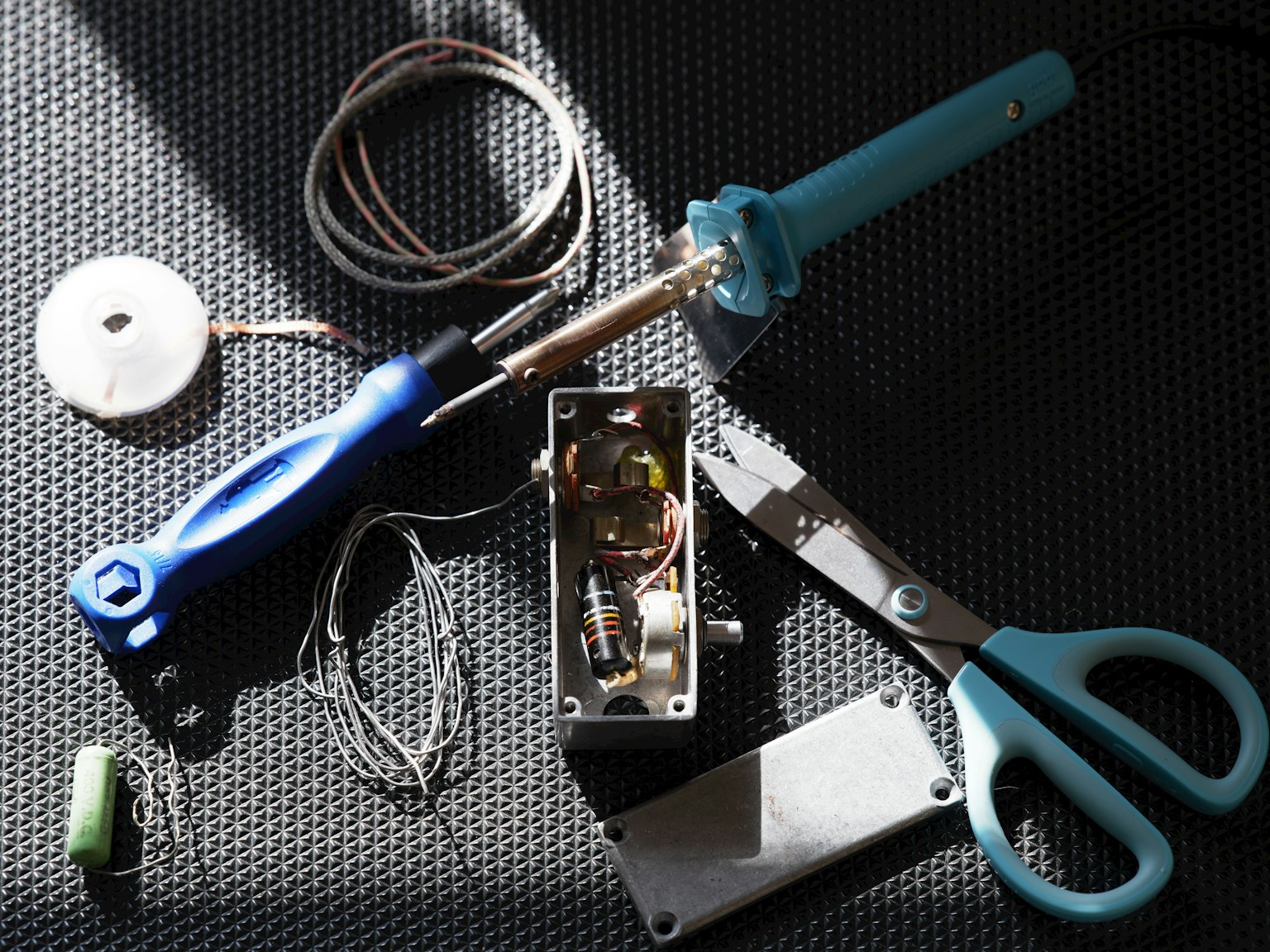 Immagine di uno spazio di lavoro con strumenti e componenti elettronici sparsi