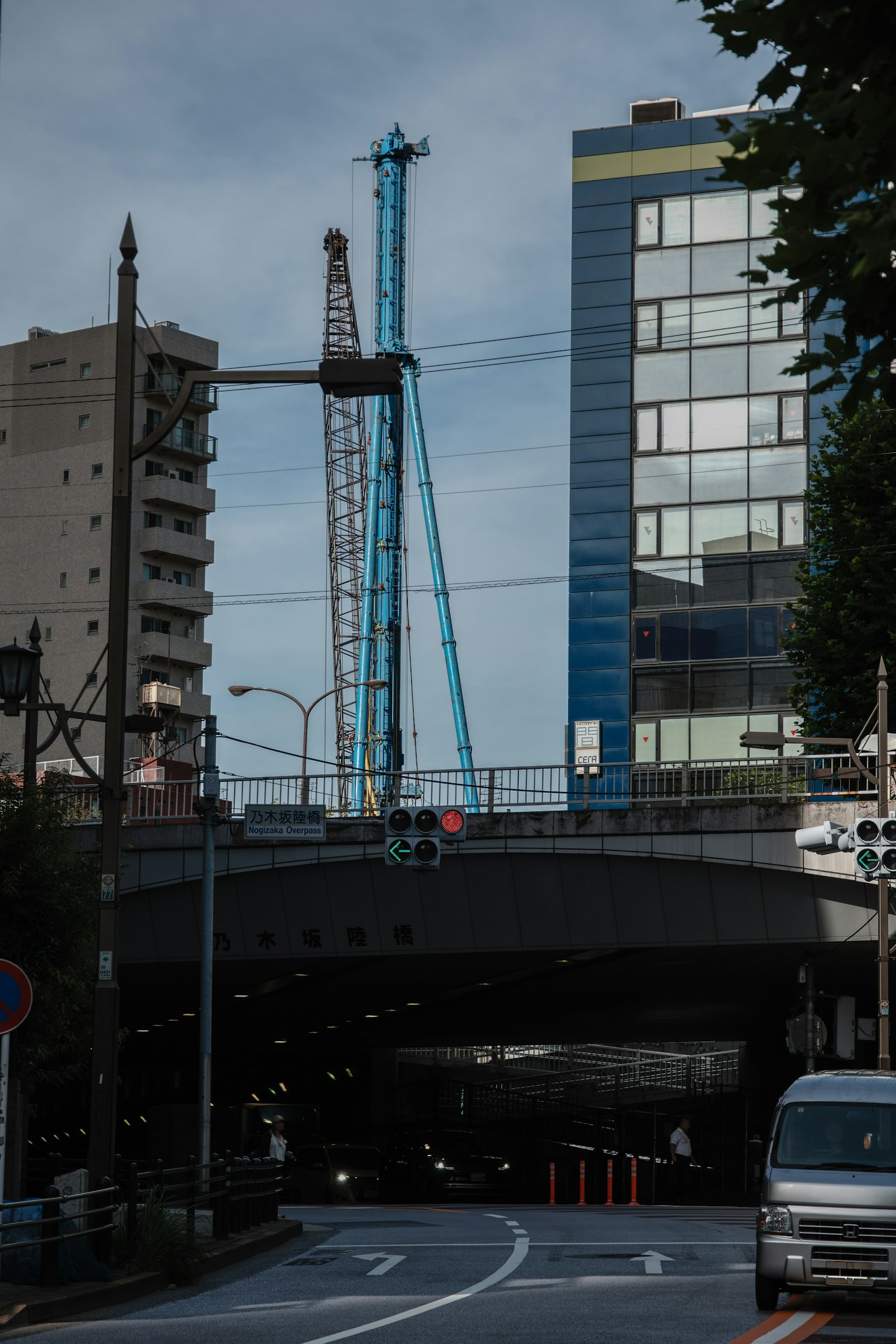 Scena urbana sotto un cavalcavia con una gru blu e edifici moderni