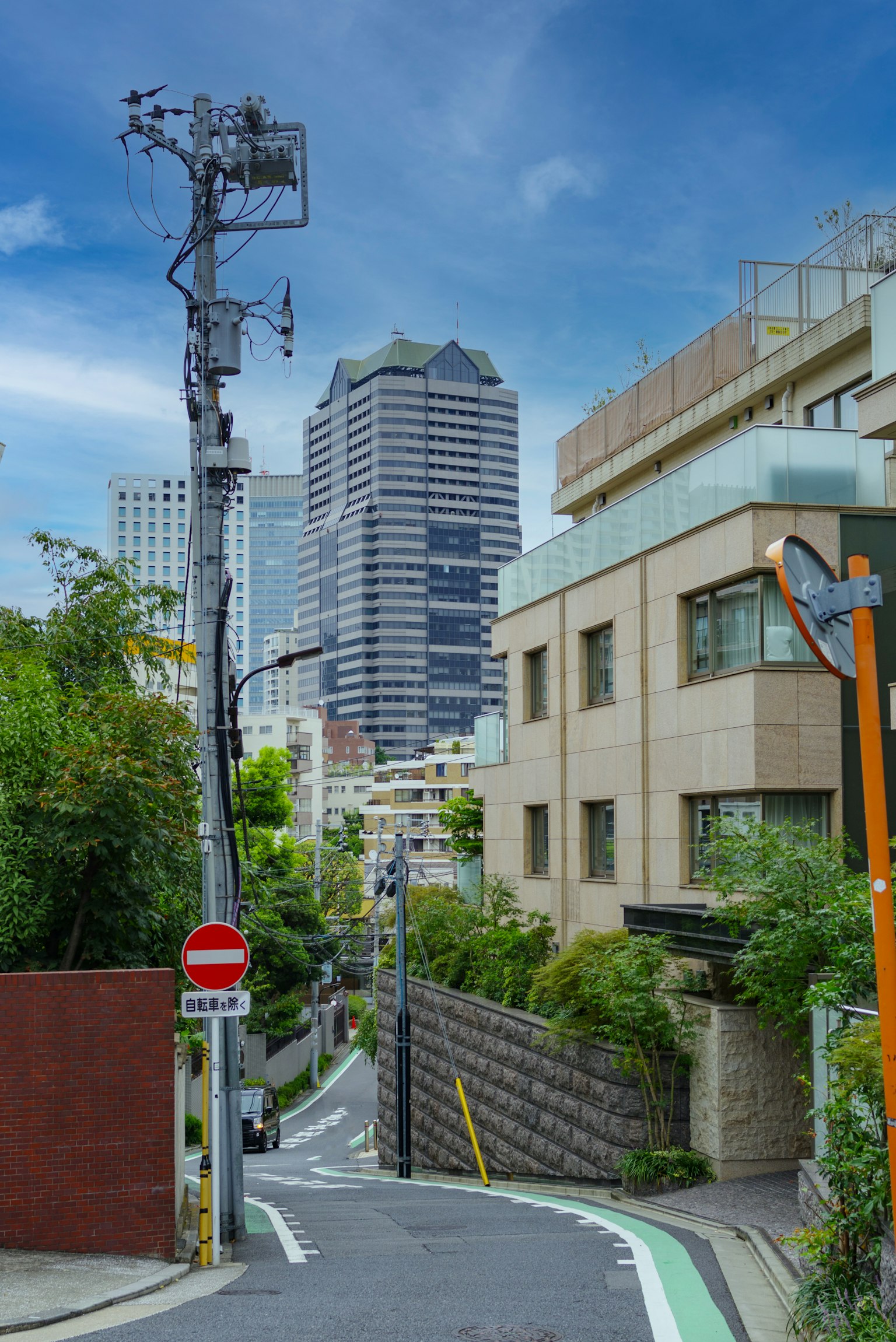 Urban landscape of Tokyo with buildings and greenery steep hill and utility pole