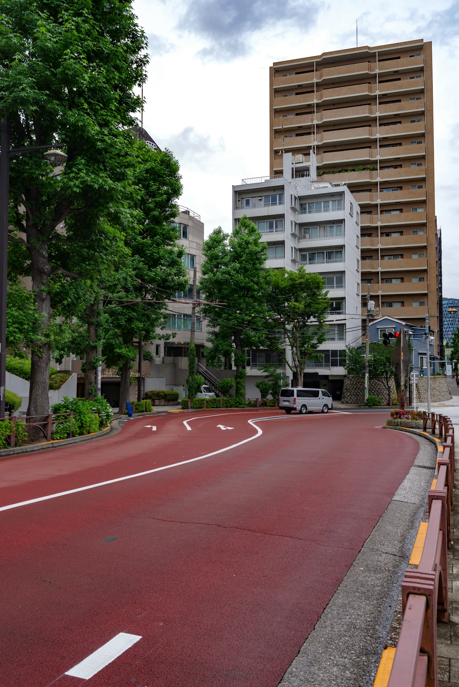 Escena urbana con una carretera pavimentada roja bordeada de árboles verdes altos edificios al fondo