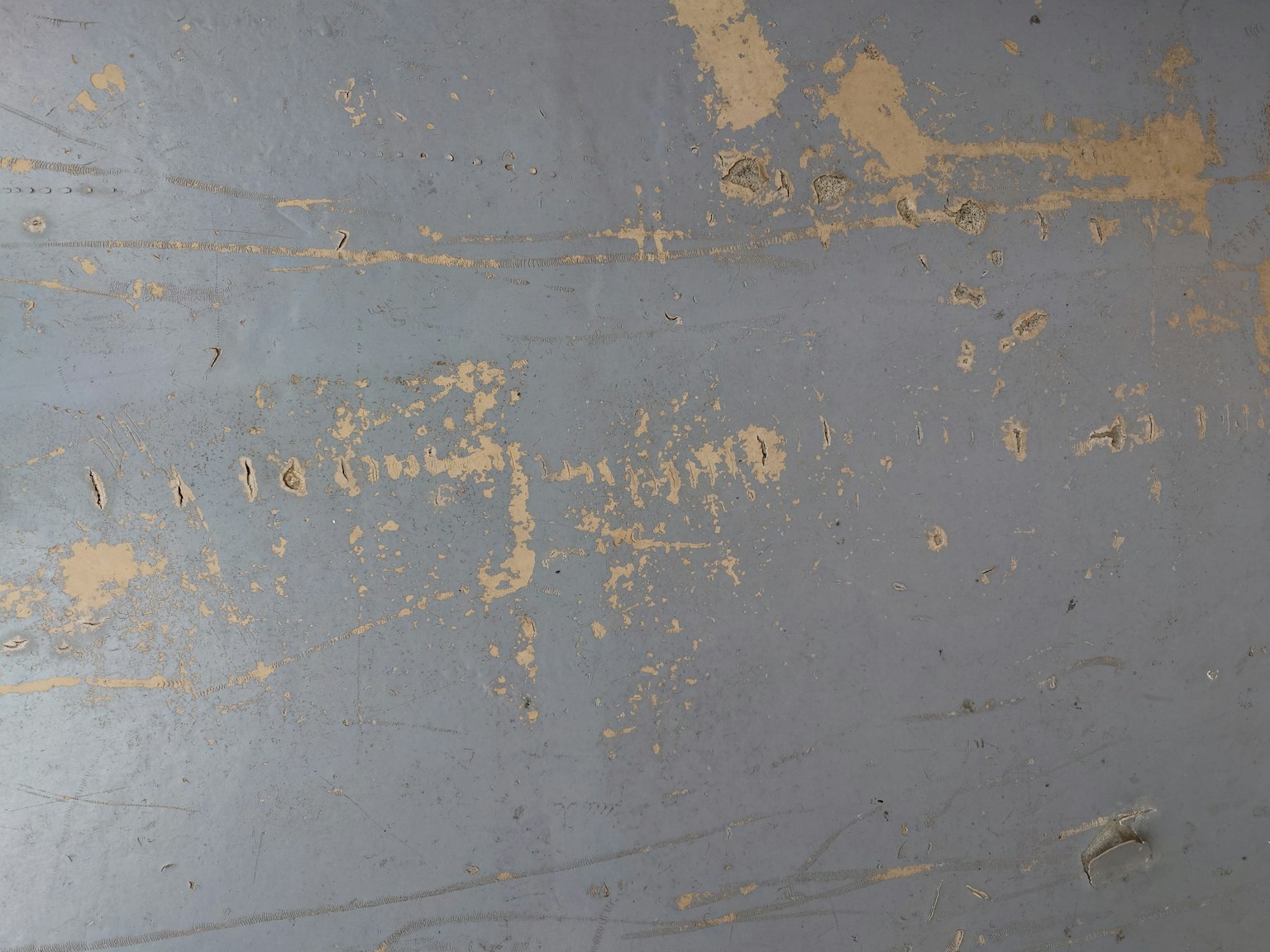 Una superficie blu con vernice scrostata e graffi visibili