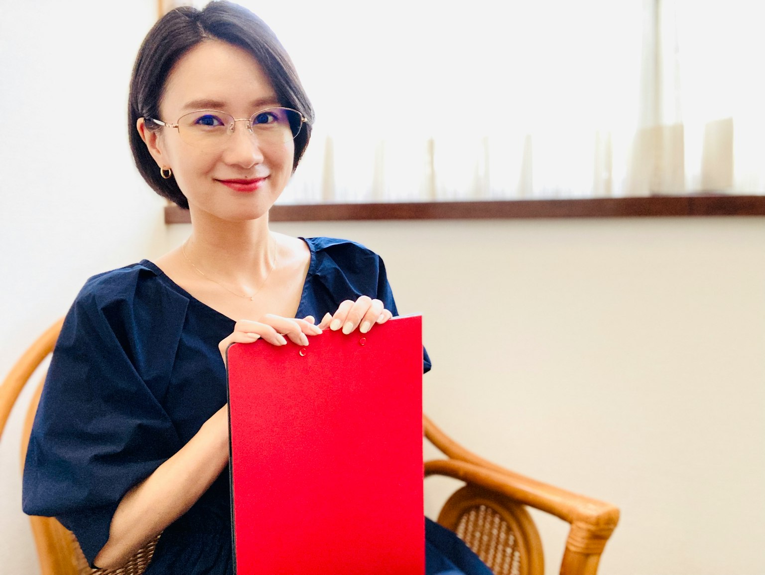 Wanita memegang folder merah duduk di kursi