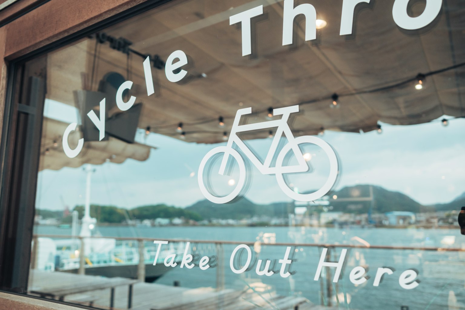 Ventana de un café temático de ciclismo con un ícono de bicicleta y un letrero de comida para llevar