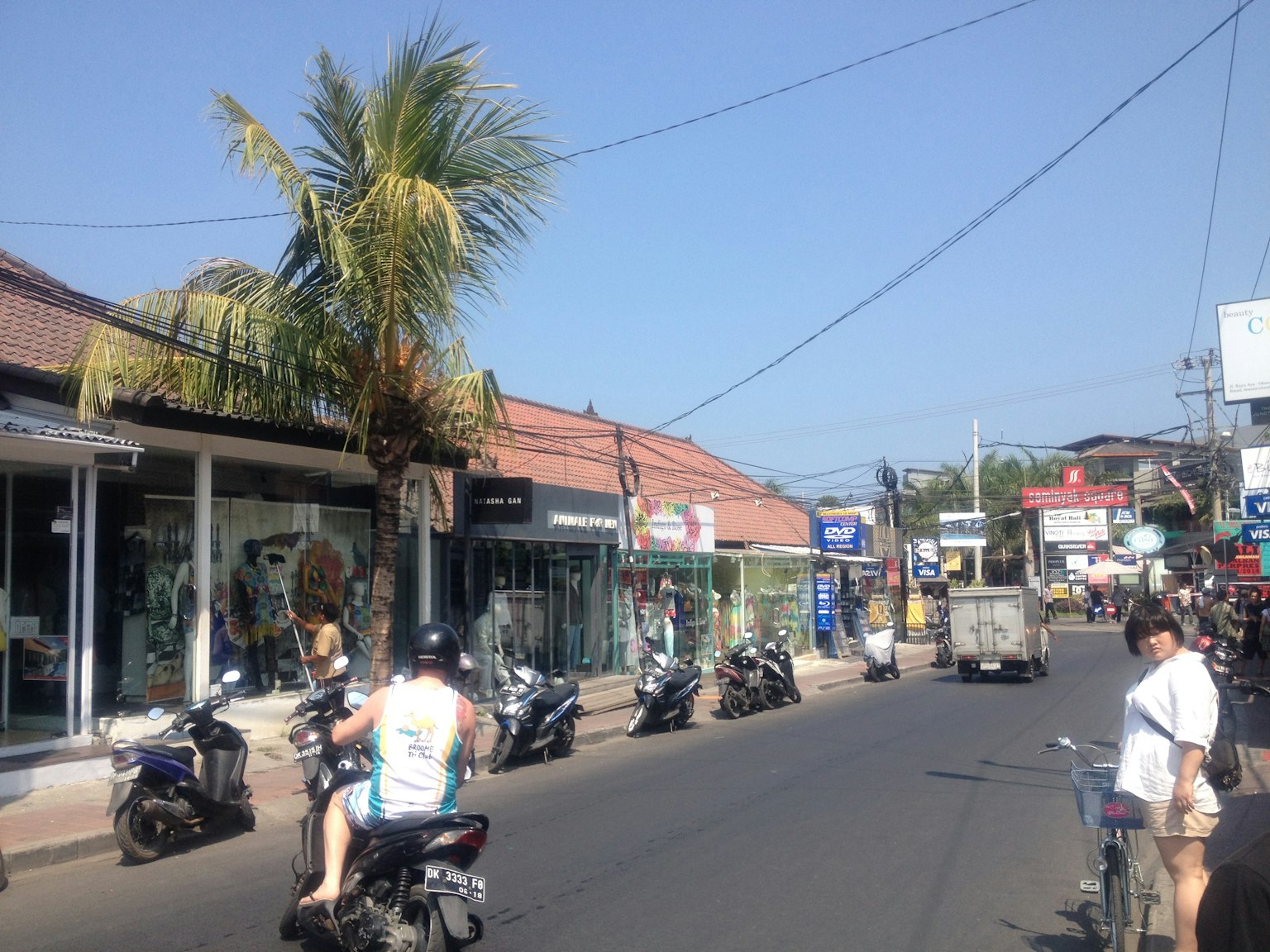 ถนนที่พลุกพล่านในบาหลีพร้อมร้านค้าและการจราจรของมอเตอร์ไซค์