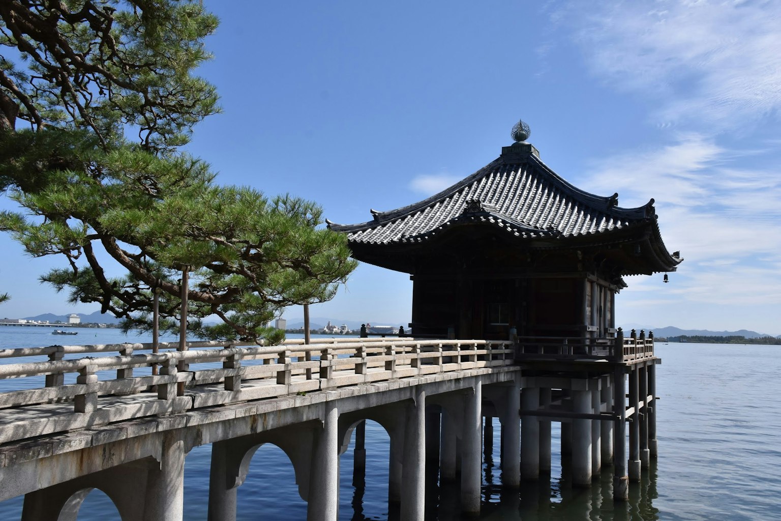 传统中国风格建筑位于宁静湖面上，旁边有木桥