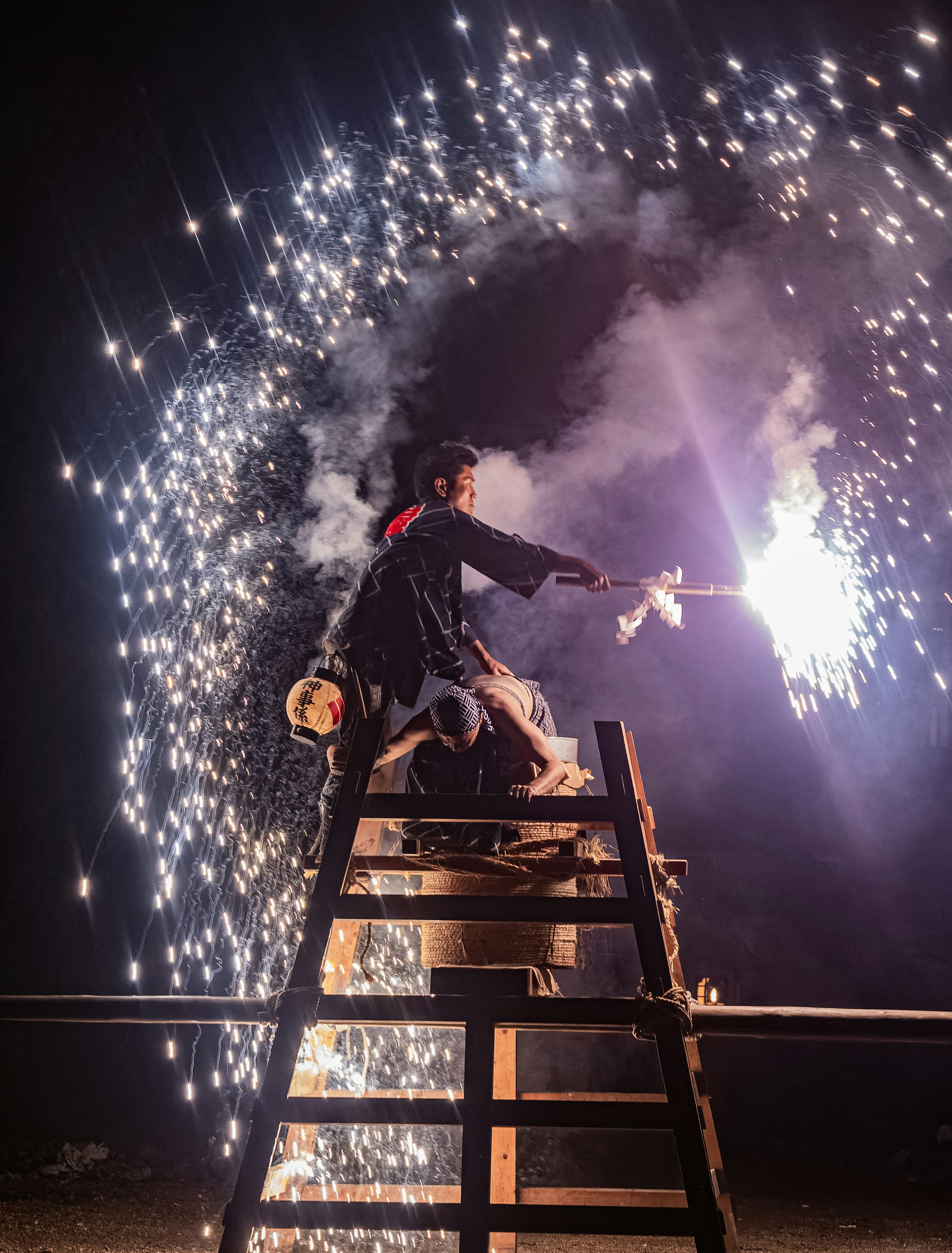 はしごに乗って花火を手にするパフォーマーの夜の演出