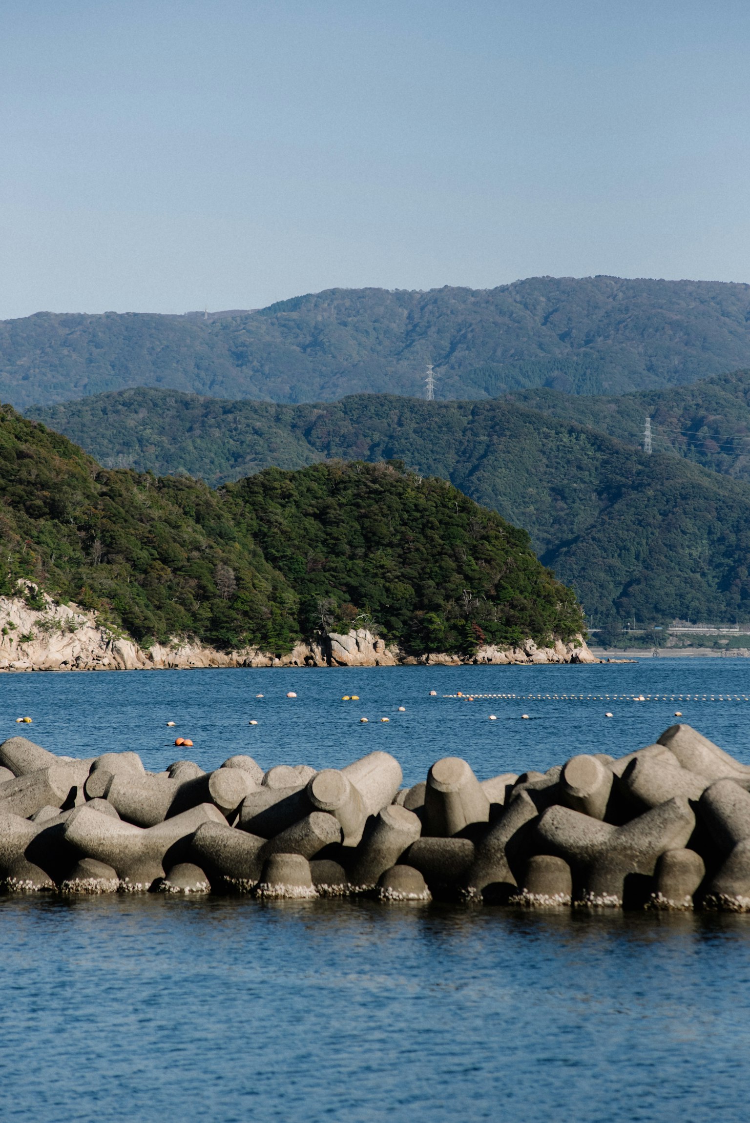 Breakwater beton dengan laut biru dan latar belakang pegunungan