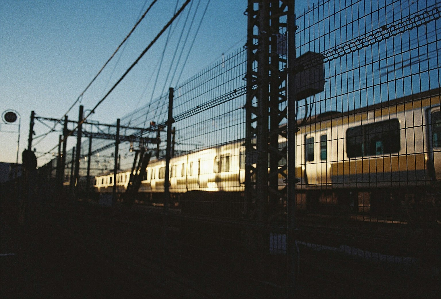 Silhouette of a train along the tracks at dusk with a power pole