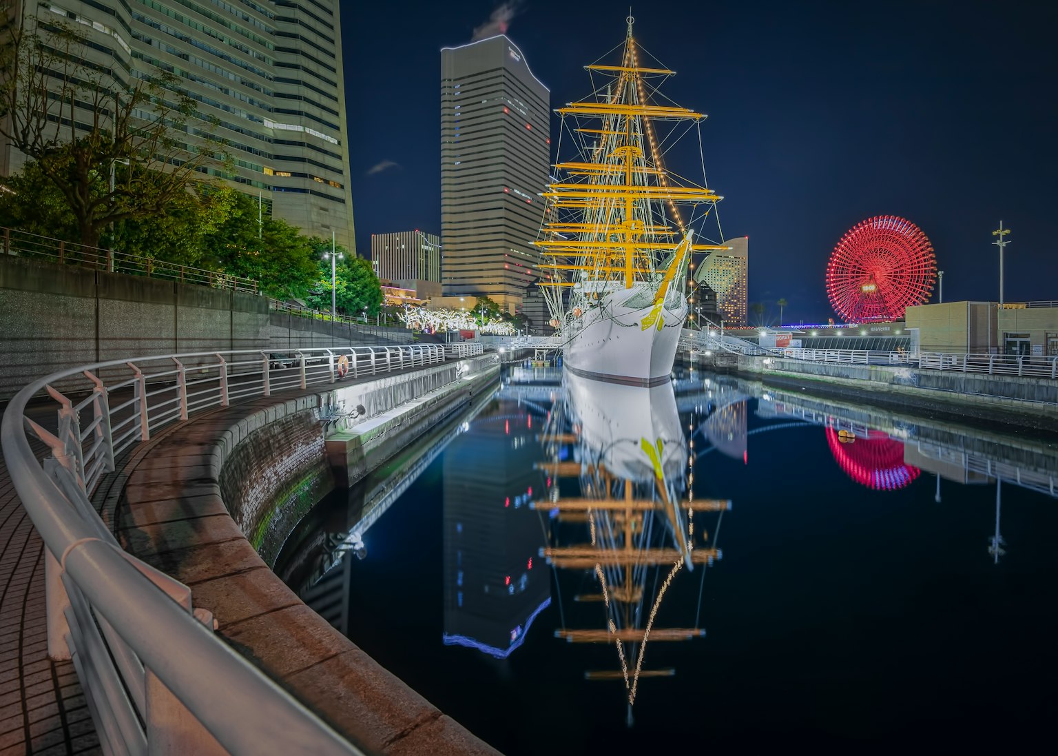 夜間照亮的帆船與水中的倒影和周圍建築