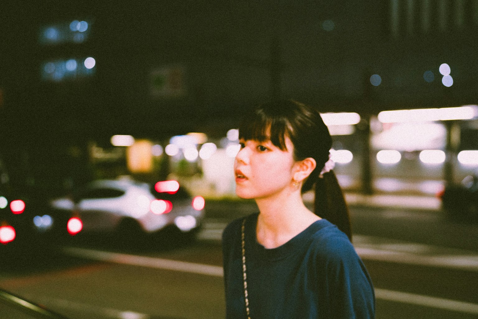夜晚城市中走动的女性肖像，背景有模糊的汽车灯光