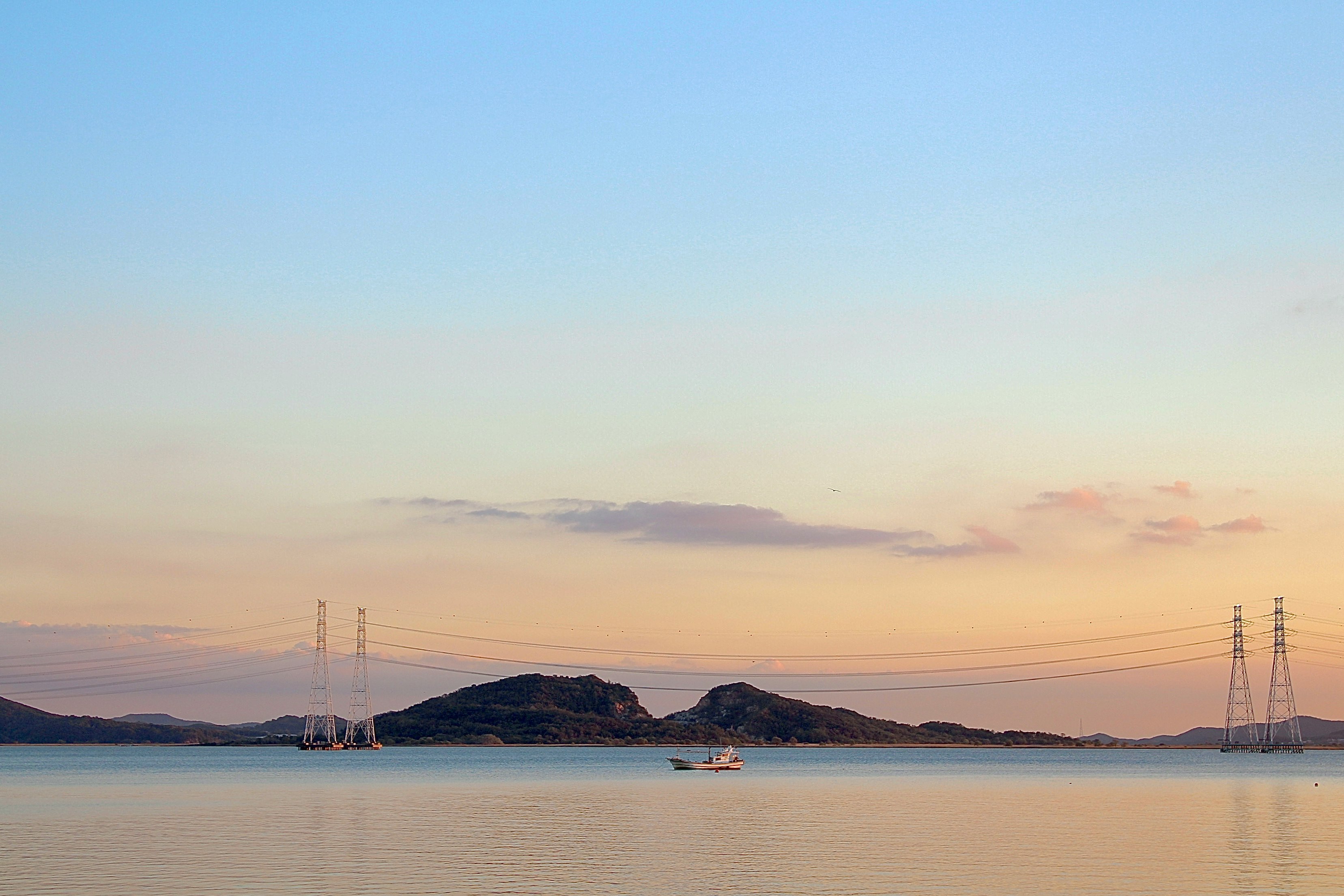夕暮れの穏やかな海と小さな島、停泊するヨットのある風景