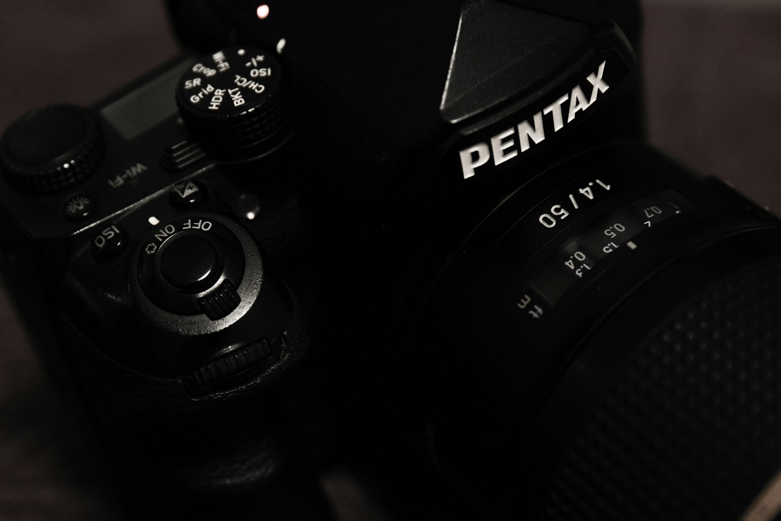 Gambar close-up kamera Pentax dengan bodi hitam dan lensa