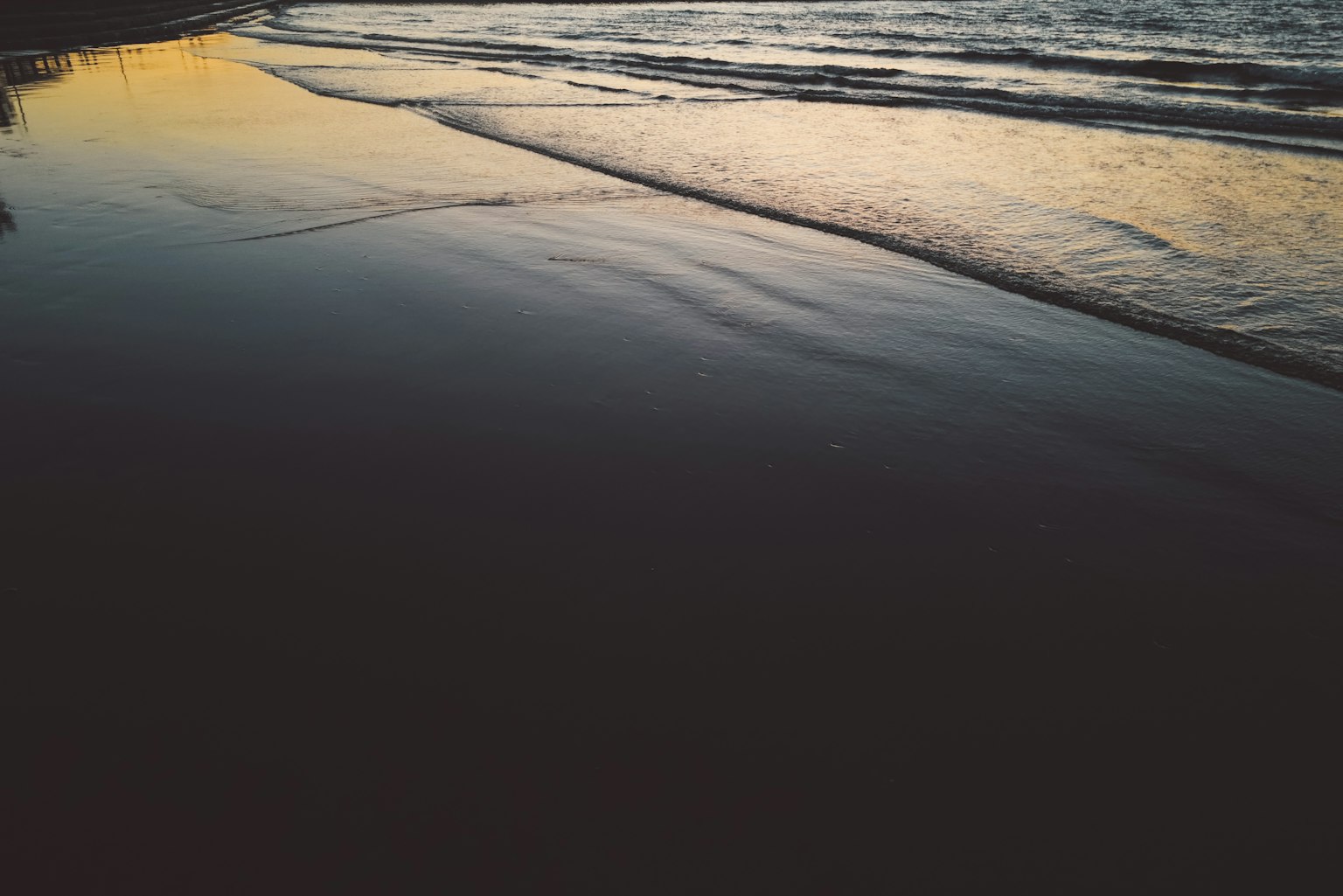 Riflesso del tramonto sulla superficie dell'acqua e silhouette della spiaggia