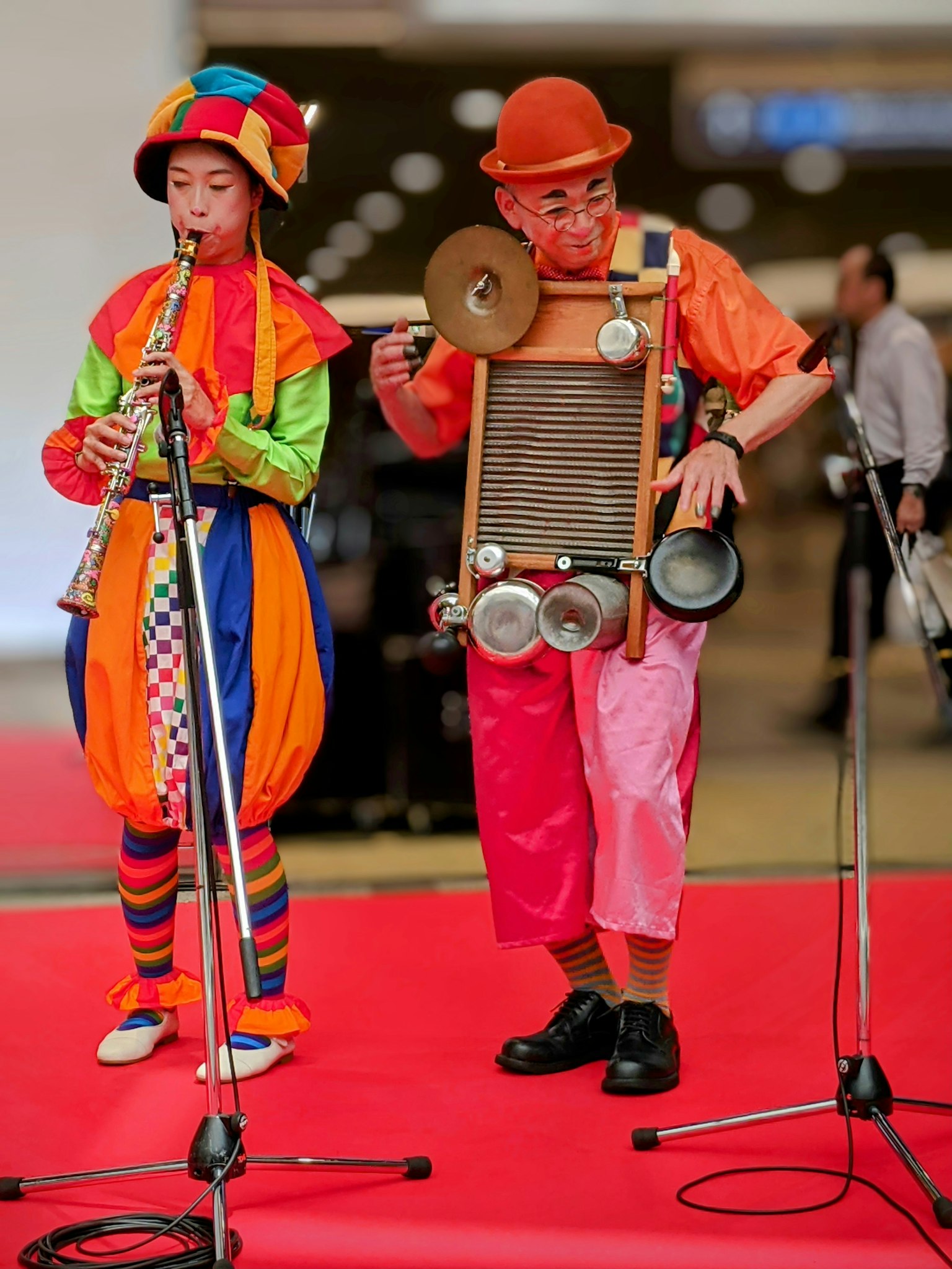 Two clowns in colorful costumes performing music