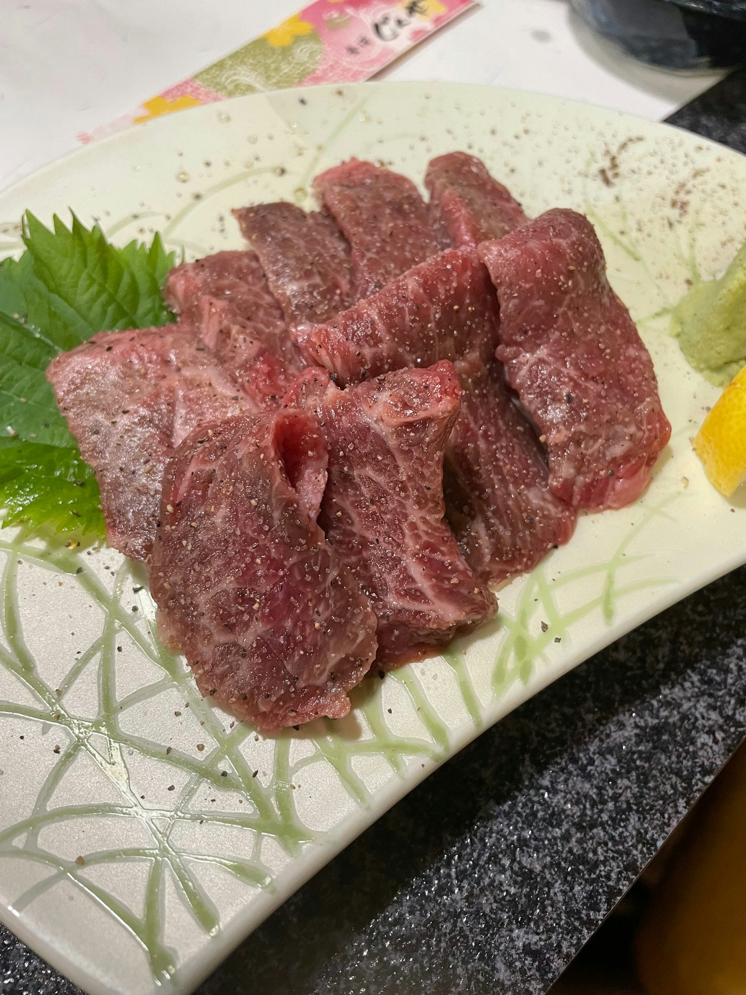 新鲜肉片摆放在盘子上，配有绿叶和柠檬片
