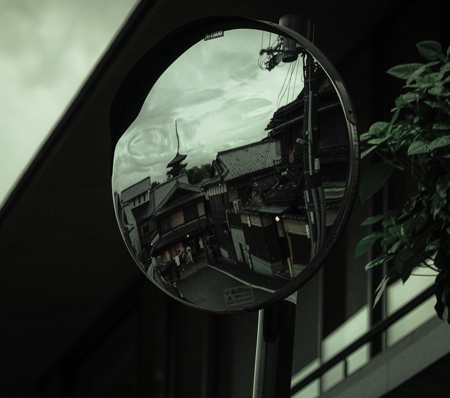 Mirror reflecting urban scenery with a moody atmosphere and green tones