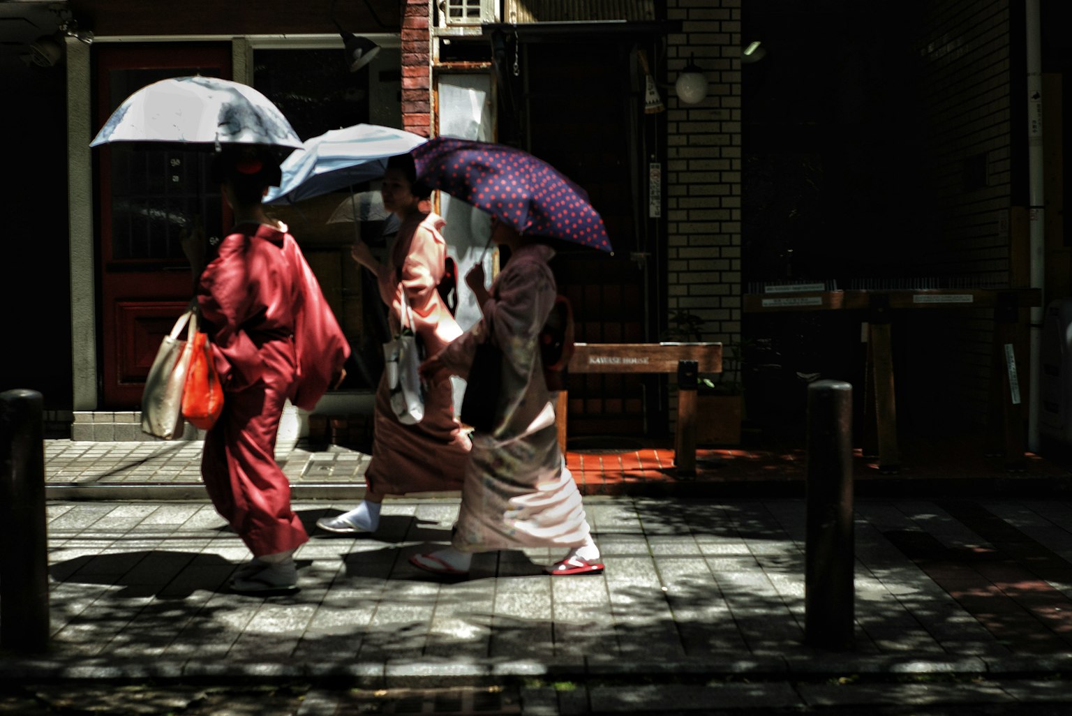 Women in kimonos walking with umbrellas on a city street