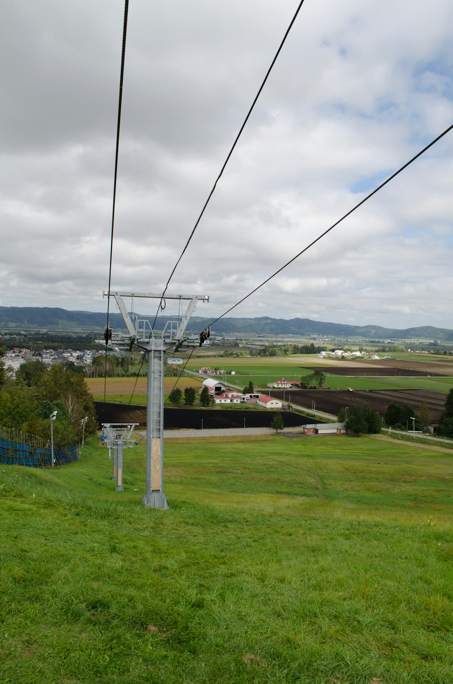 Blick von einem Skilift auf grüne Hügel und landwirtschaftliche Flächen